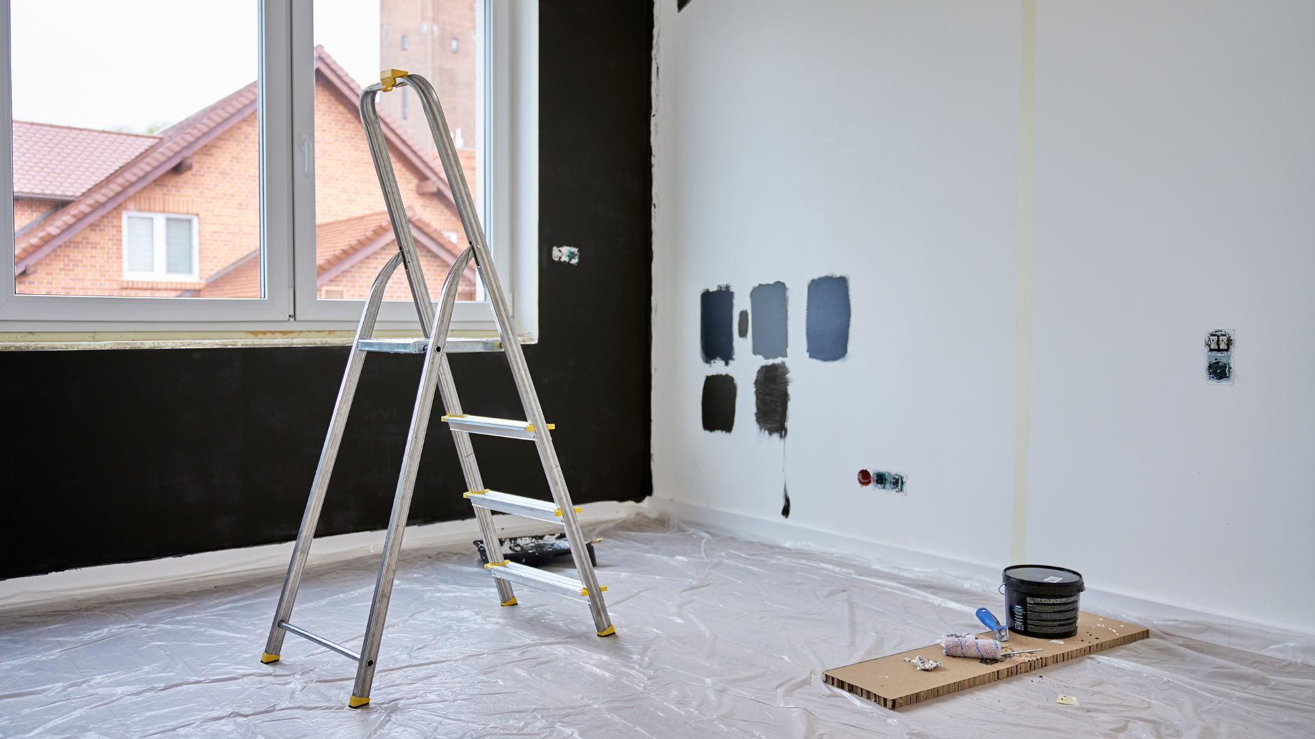 Room being painted: one black wall, white walls, ladder, paint samples.
