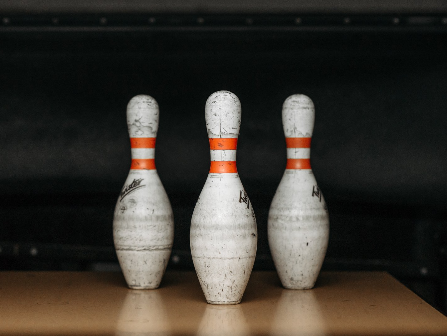 Auf einem Holztisch stehen drei Bowlingkegel.