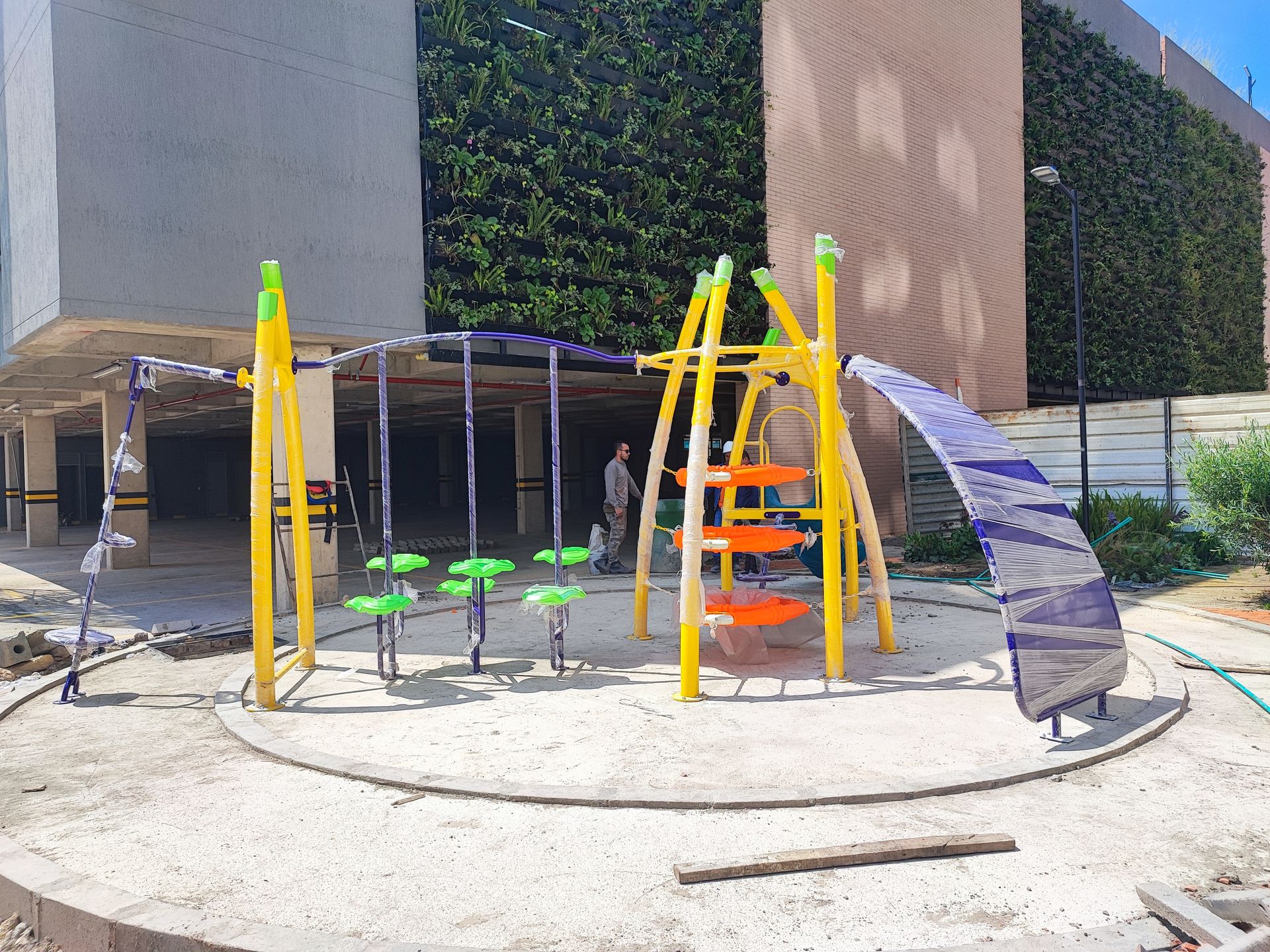 Un bote de basura de acero inoxidable está sobre una acera de ladrillos al lado de una calle.