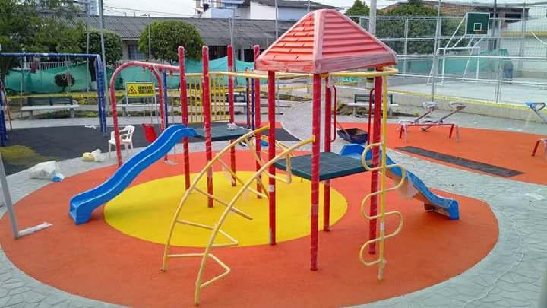 Un colorido parque infantil con toboganes y tubos frente a un edificio.