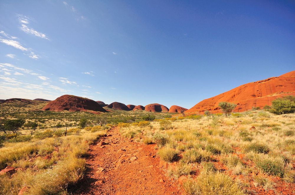 A Dirt Road In The Middle Of A Desert With Mountains In The Background — PK Crash Repairs In Uluru, NT