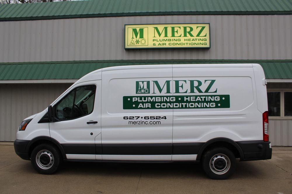 A white merz van is parked in front of a building