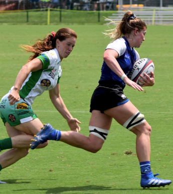 Women's rugby player runs the ball hard