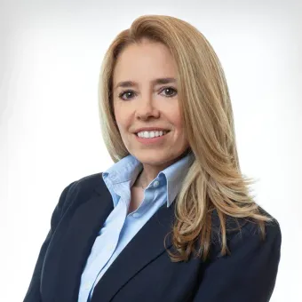 A woman in a suit and blue shirt is smiling for the camera