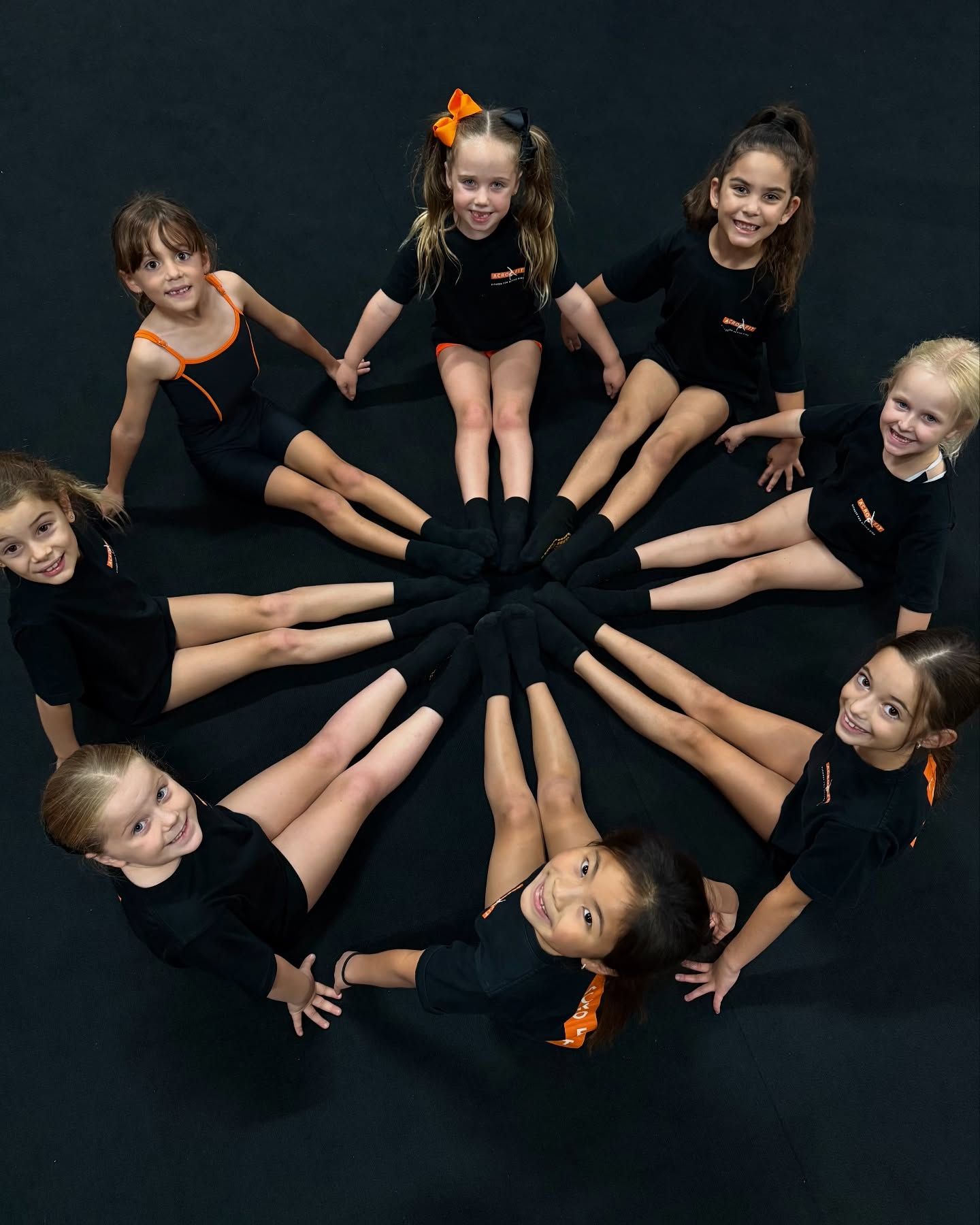 A group of young girls are sitting in a circle with their legs crossed.