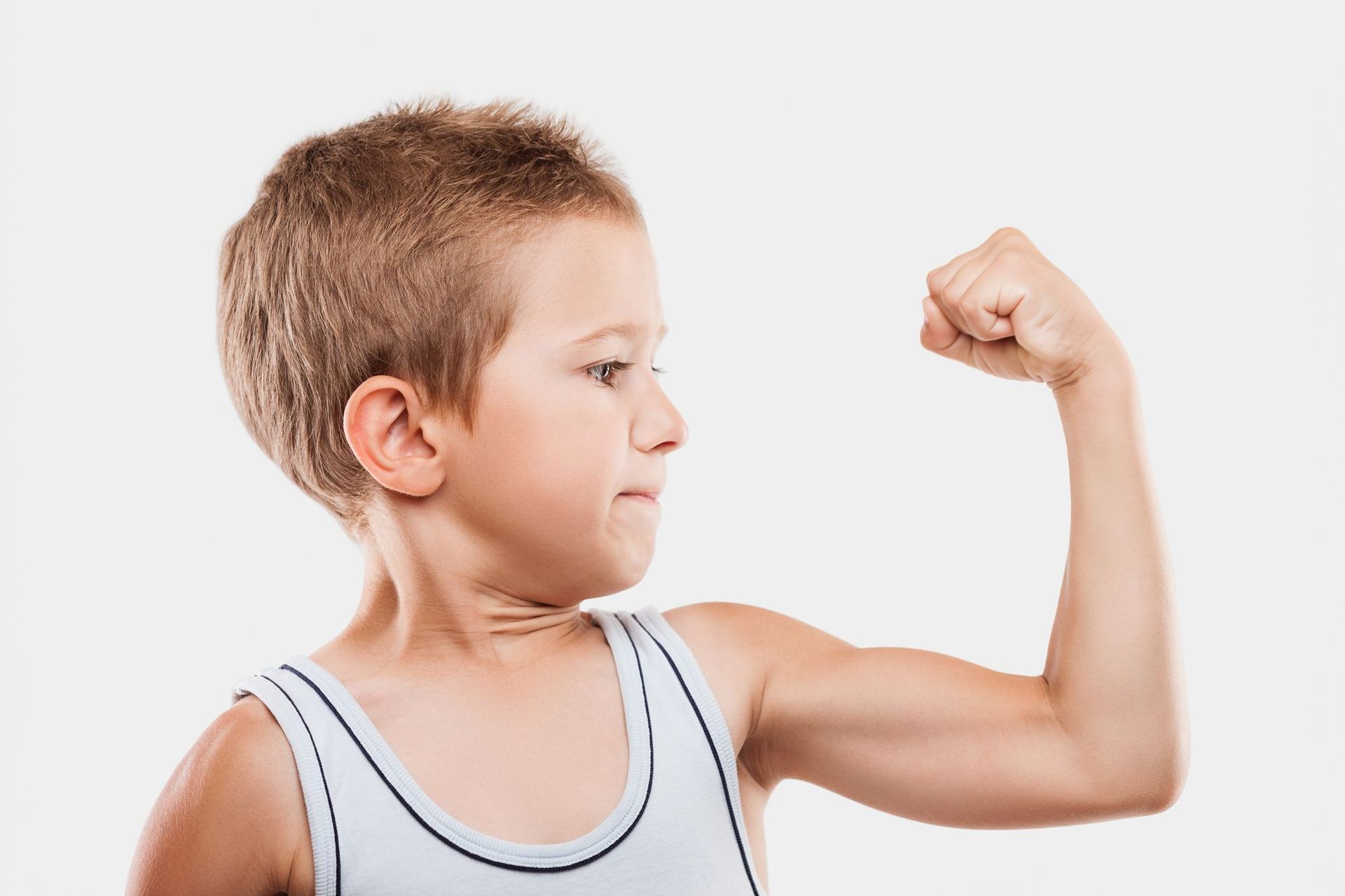 A young boy is flexing his muscles on a white background.