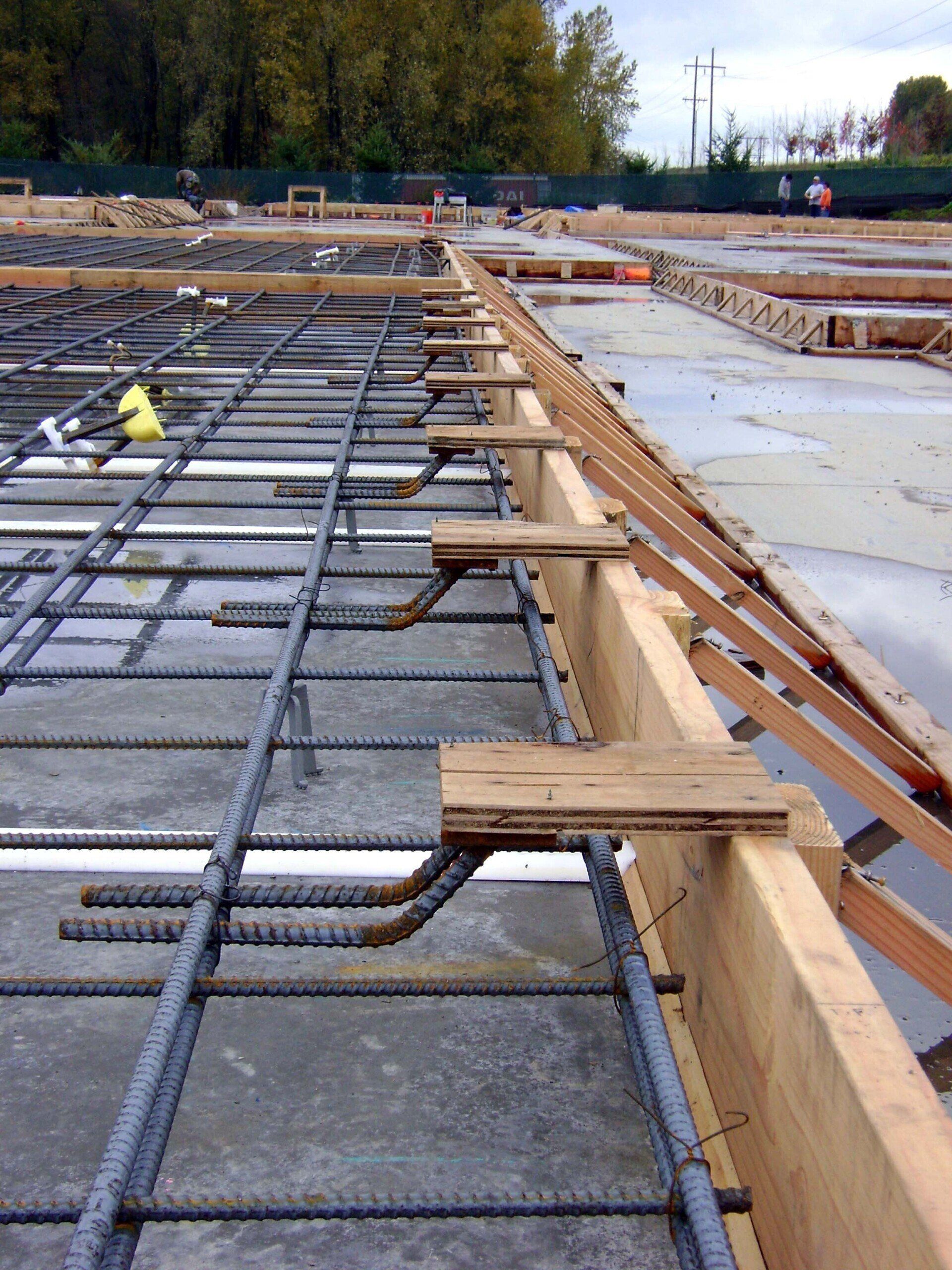 Construction site with rebar grid and wooden forms for a concrete slab.