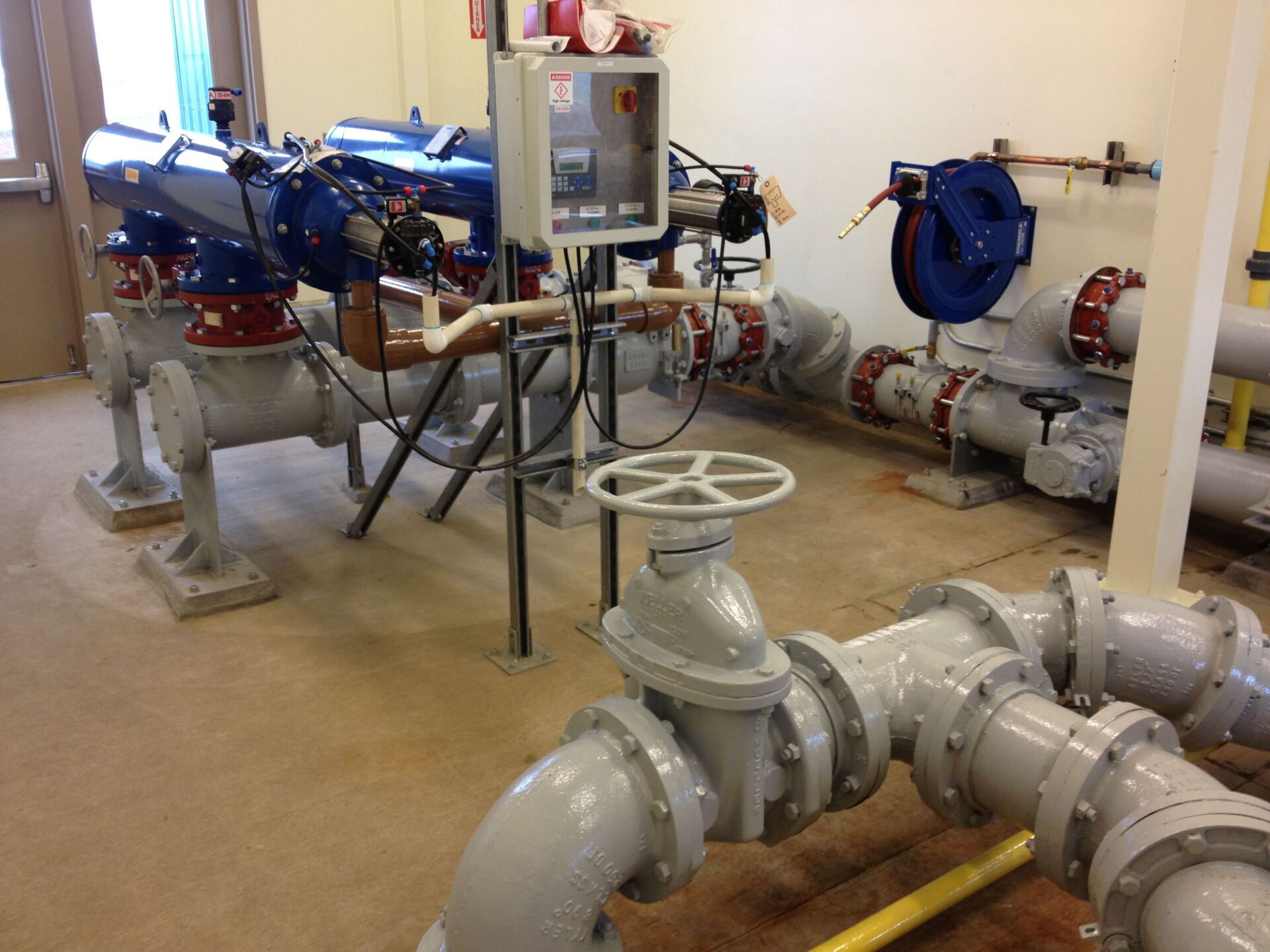 Pipes and filtration equipment in an industrial setting, with a control panel and valves visible.