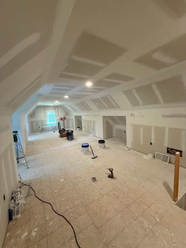 Interior room under construction with exposed drywall and unfinished floor.