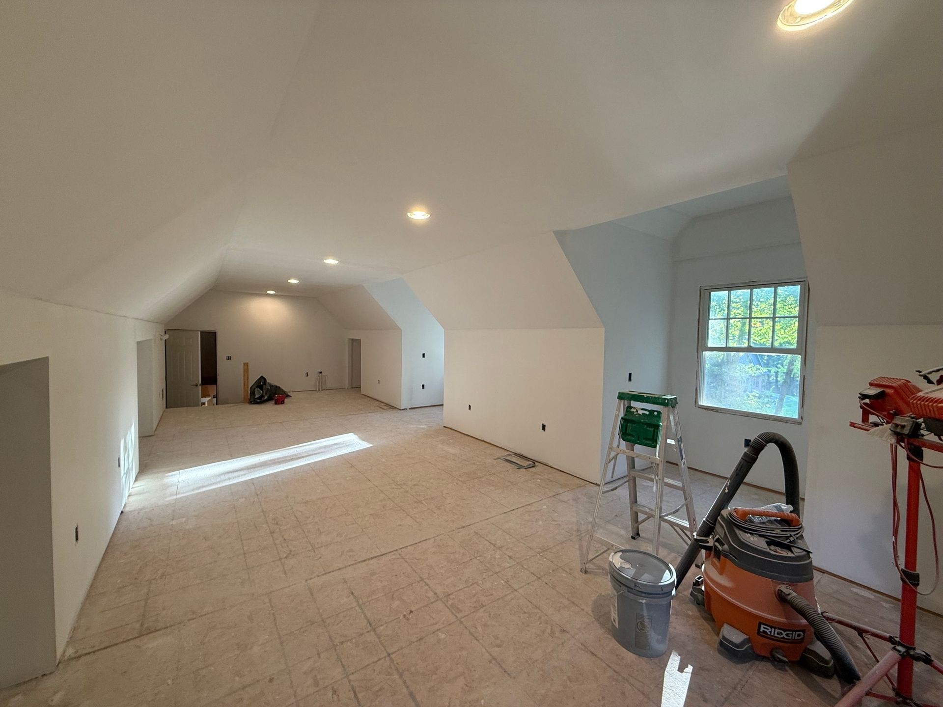 Interior of a room under construction, with white walls, bare floor, and exposed wires.