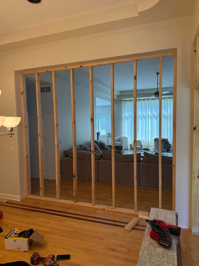 Unfinished interior wall with exposed studs and a view into a bedroom behind it