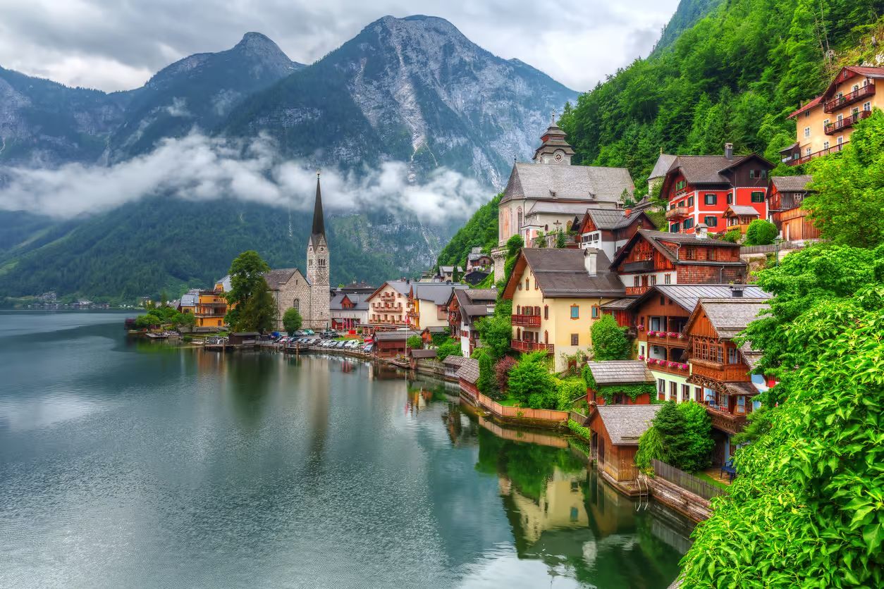 Hallstatt mit farbenfrohen Häusern, Kirchturm und Bergen, die sich im ruhigen Wasser spiegeln