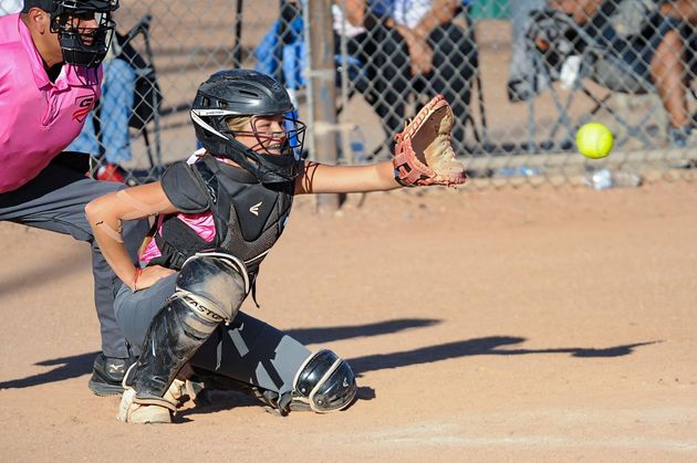Baseball player sliding into home plate, catcher in front. Blue and gold uniforms, action shot.