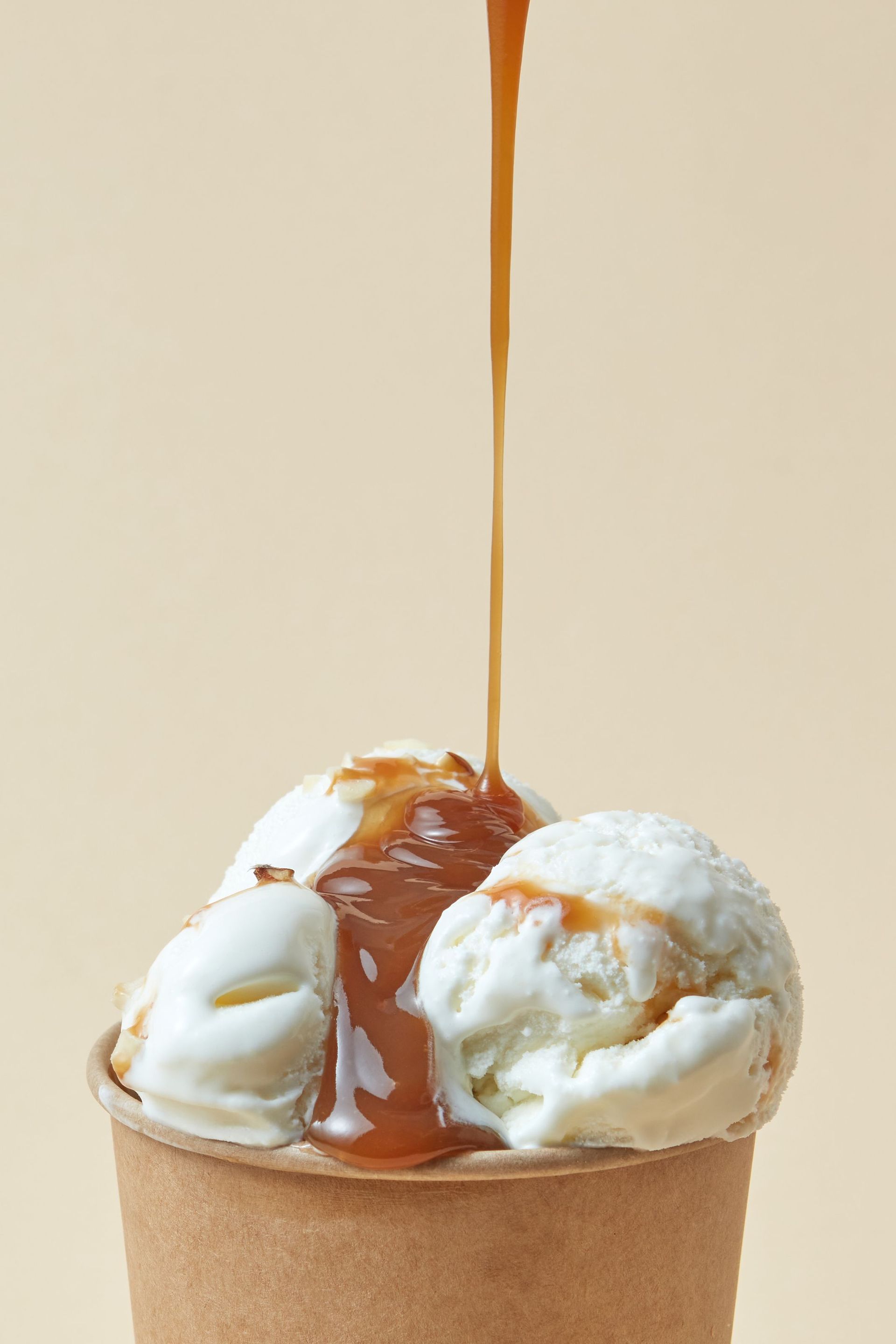 Helado de vainilla en un vaso de gofre cubierto con salsa de caramelo.