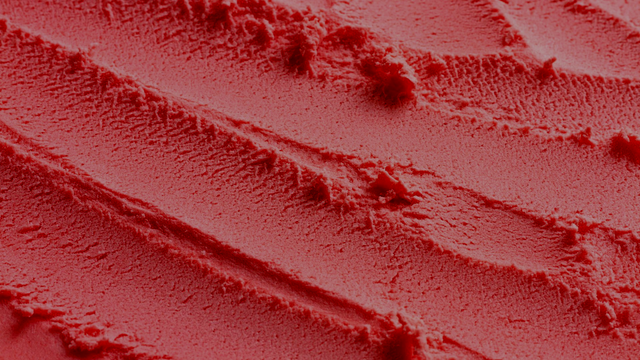 Primer plano de dunas de arena rojizas con textura ondulada y rocas oscuras dispersas.