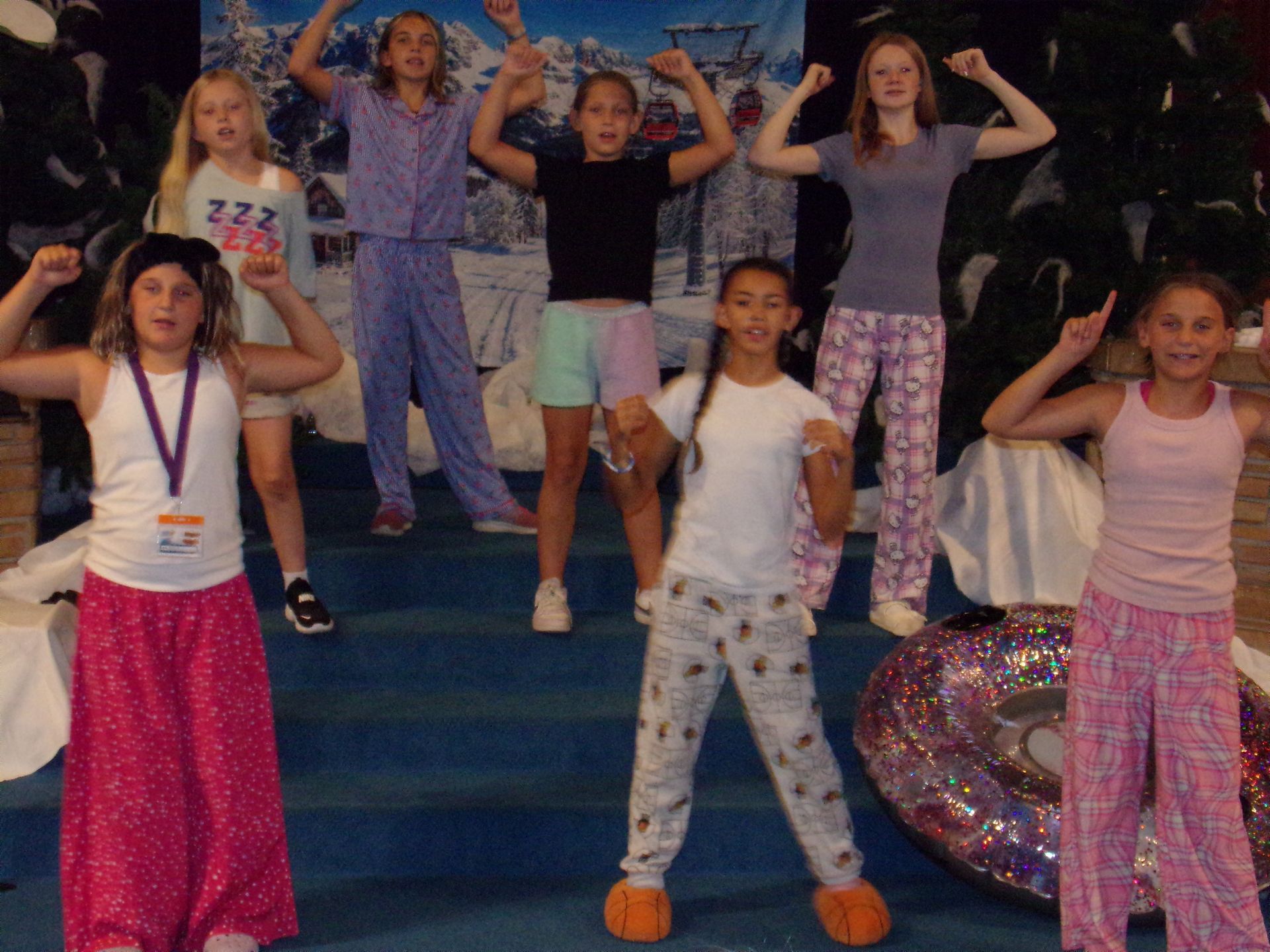 People posing on stage in colorful outfits, hands raised in a lively dance pose