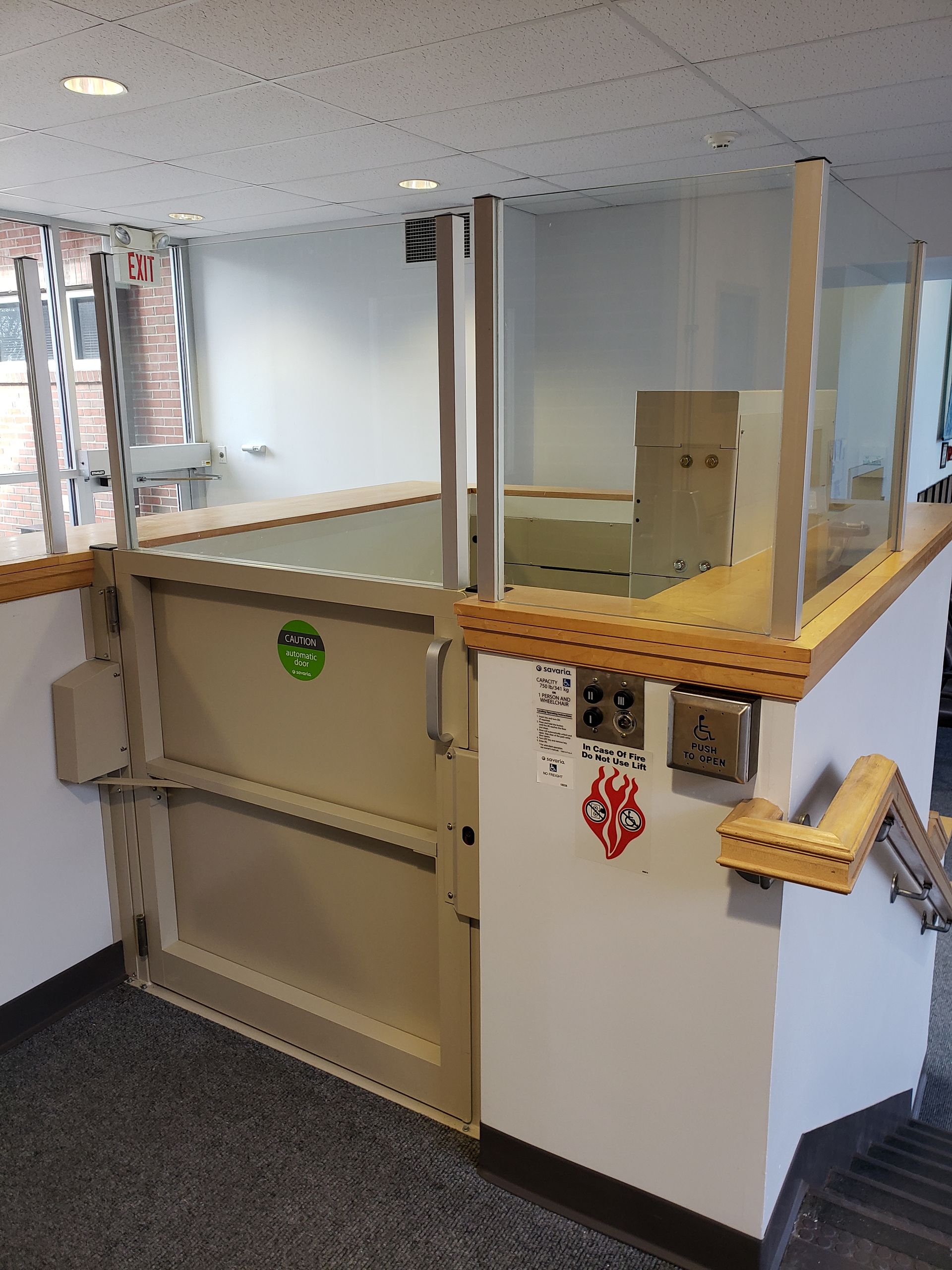 Small office service counter with clear plexiglass shield and beige cabinetry.