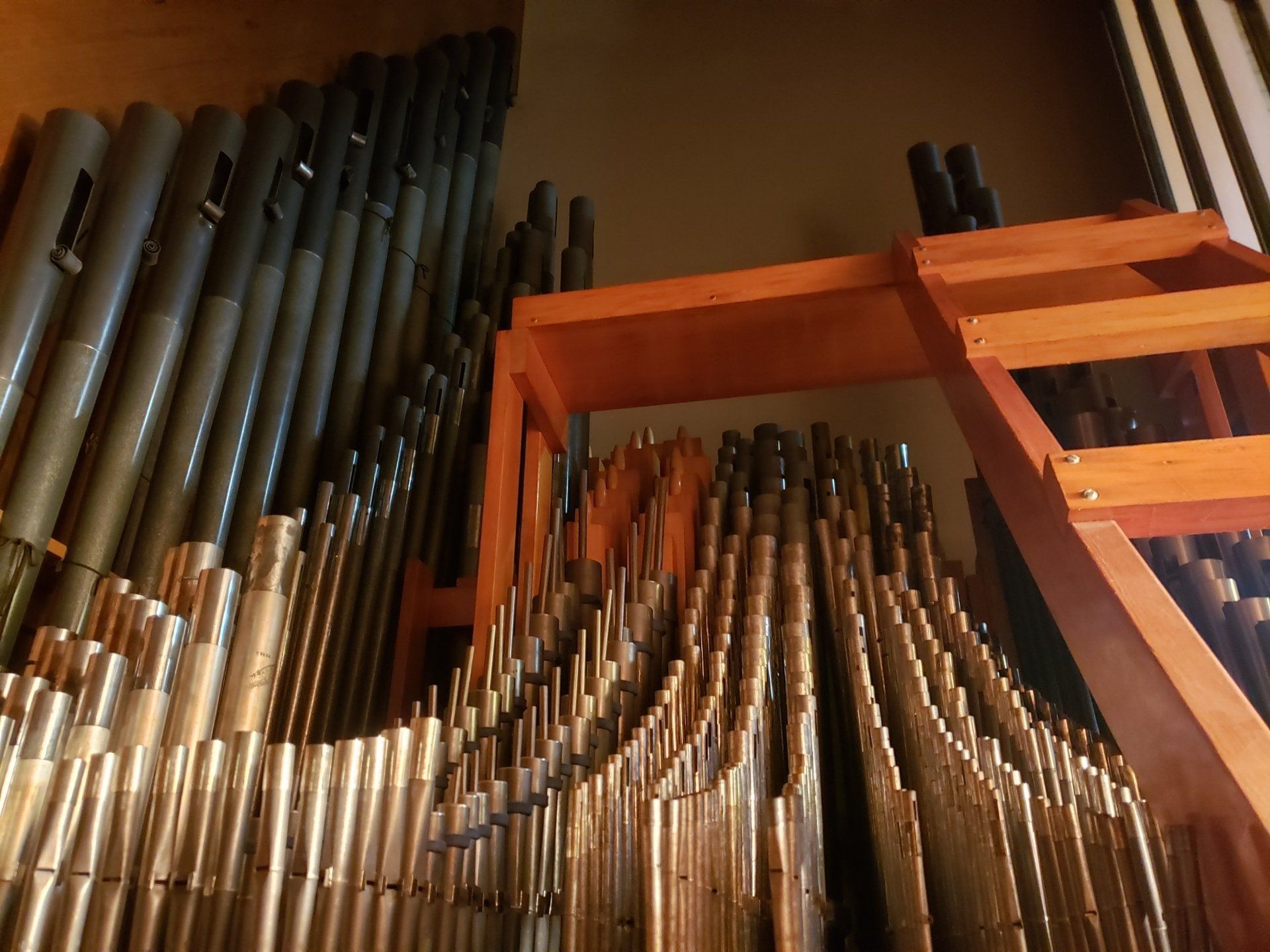Rows of silver and black organ pipes in a warm-lit wooden chamber