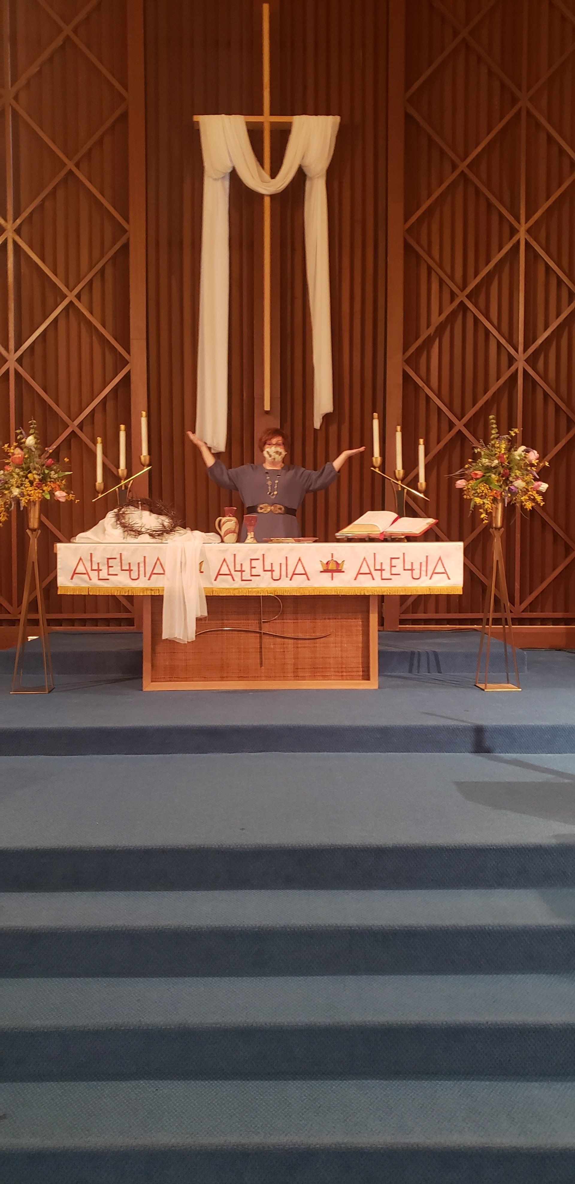 Church altar with white drapery, candles, flowers, and a central crucifix on a raised platform