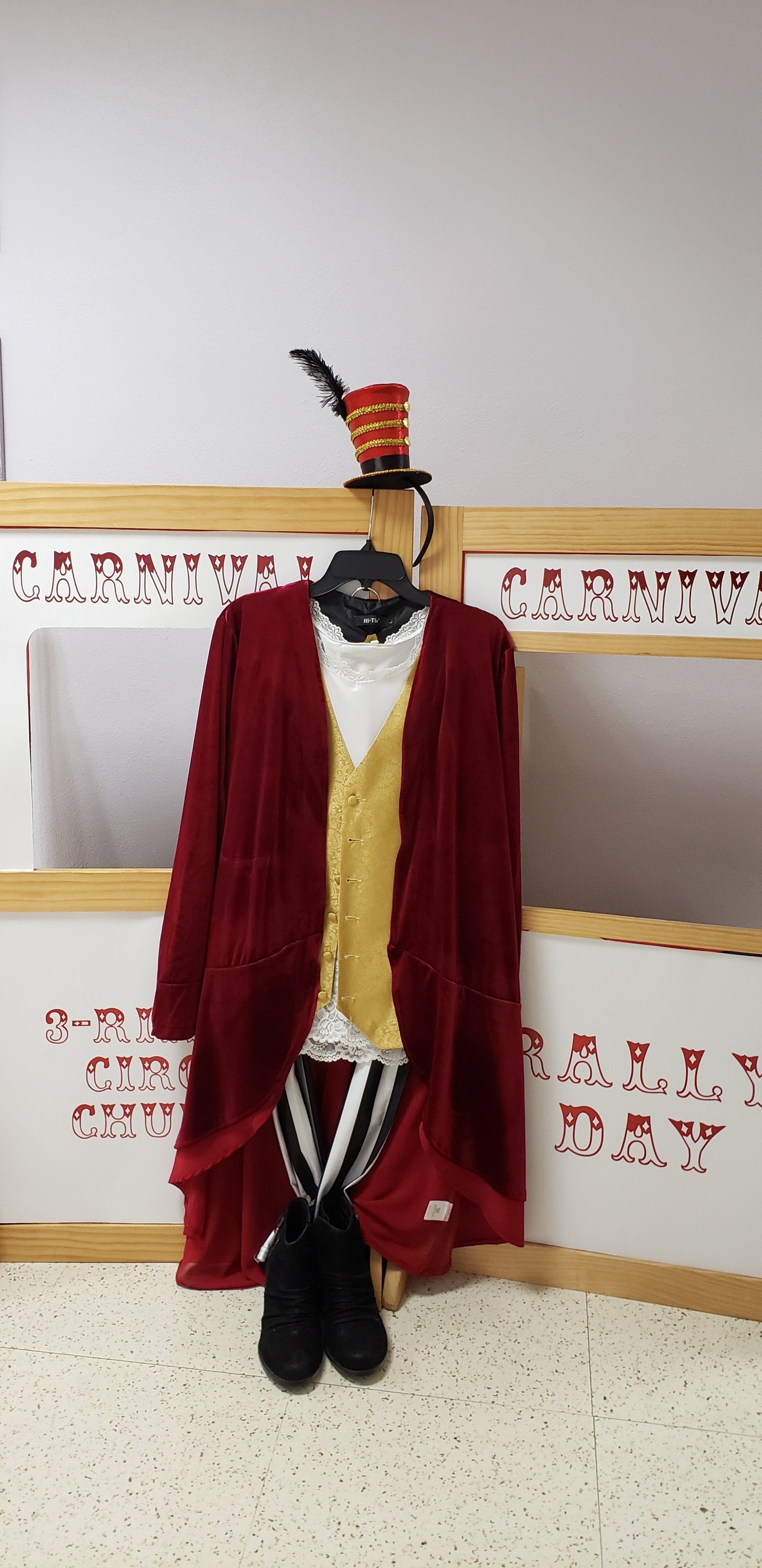 Red velvet cloak on a mannequin in a museum display, with black-and-white striped legs and a hat.