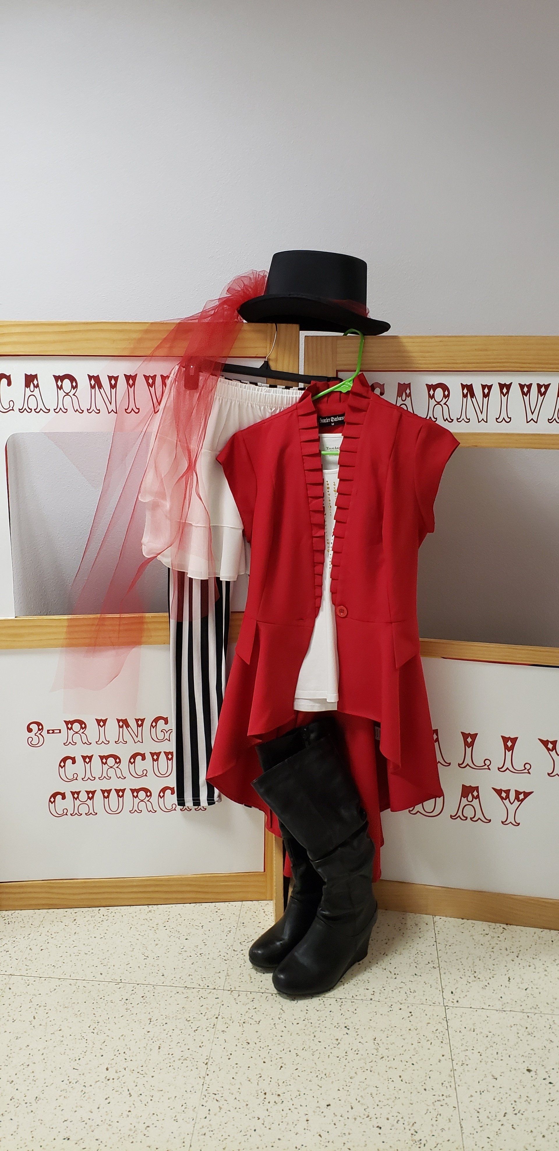 Red costume with black boots and top hat on a display stand, draped with red fabric
