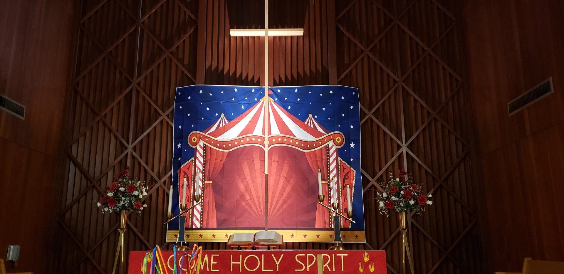 Church altar with red drapes and a sign reading “HOLY SPIRIT” inside a wooden sanctuary