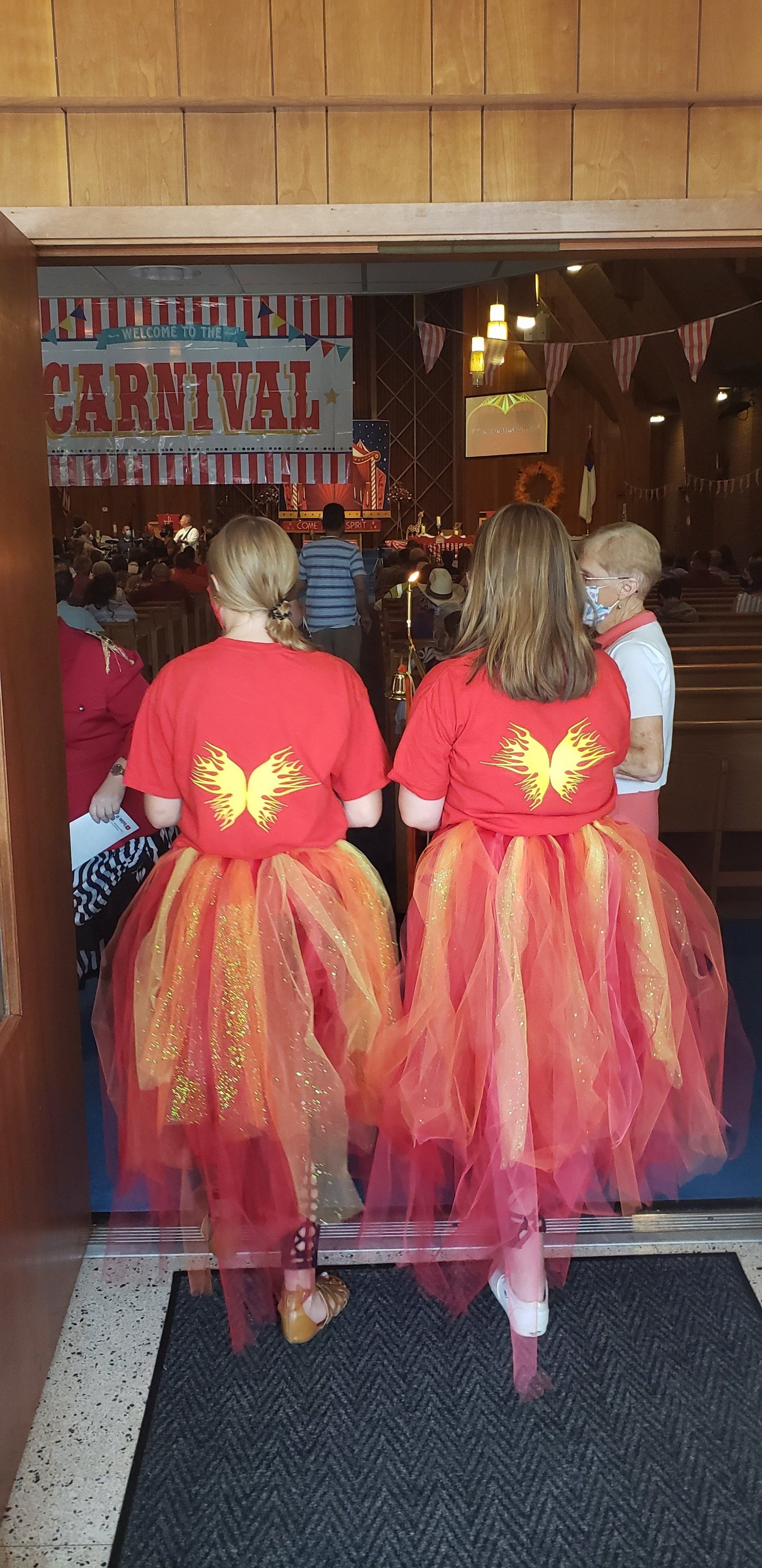 Two girls in red fairy dresses with wings entering a decorated shop doorway
