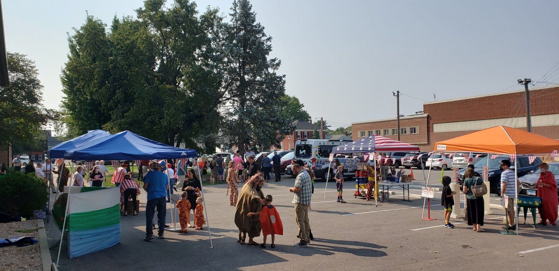 Outdoor market with people browsing vendor tents in a sunny parking lot