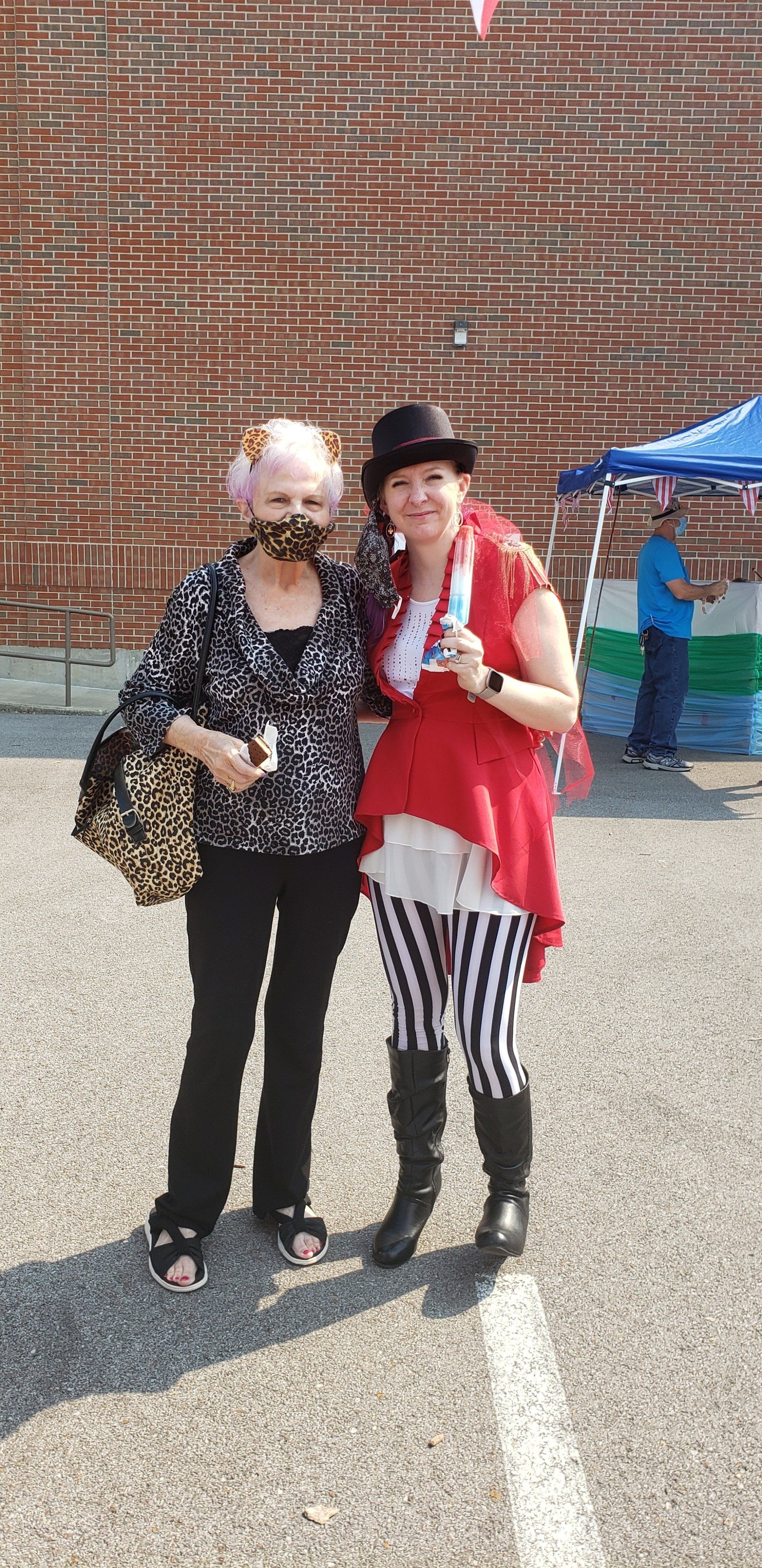 Two costumed people posing outdoors in front of a brick wall