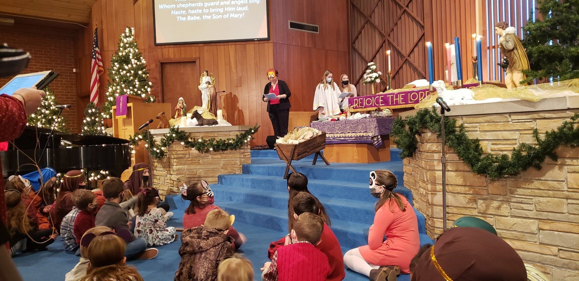Church sanctuary with people seated for a Christmas stage performance and decorated steps