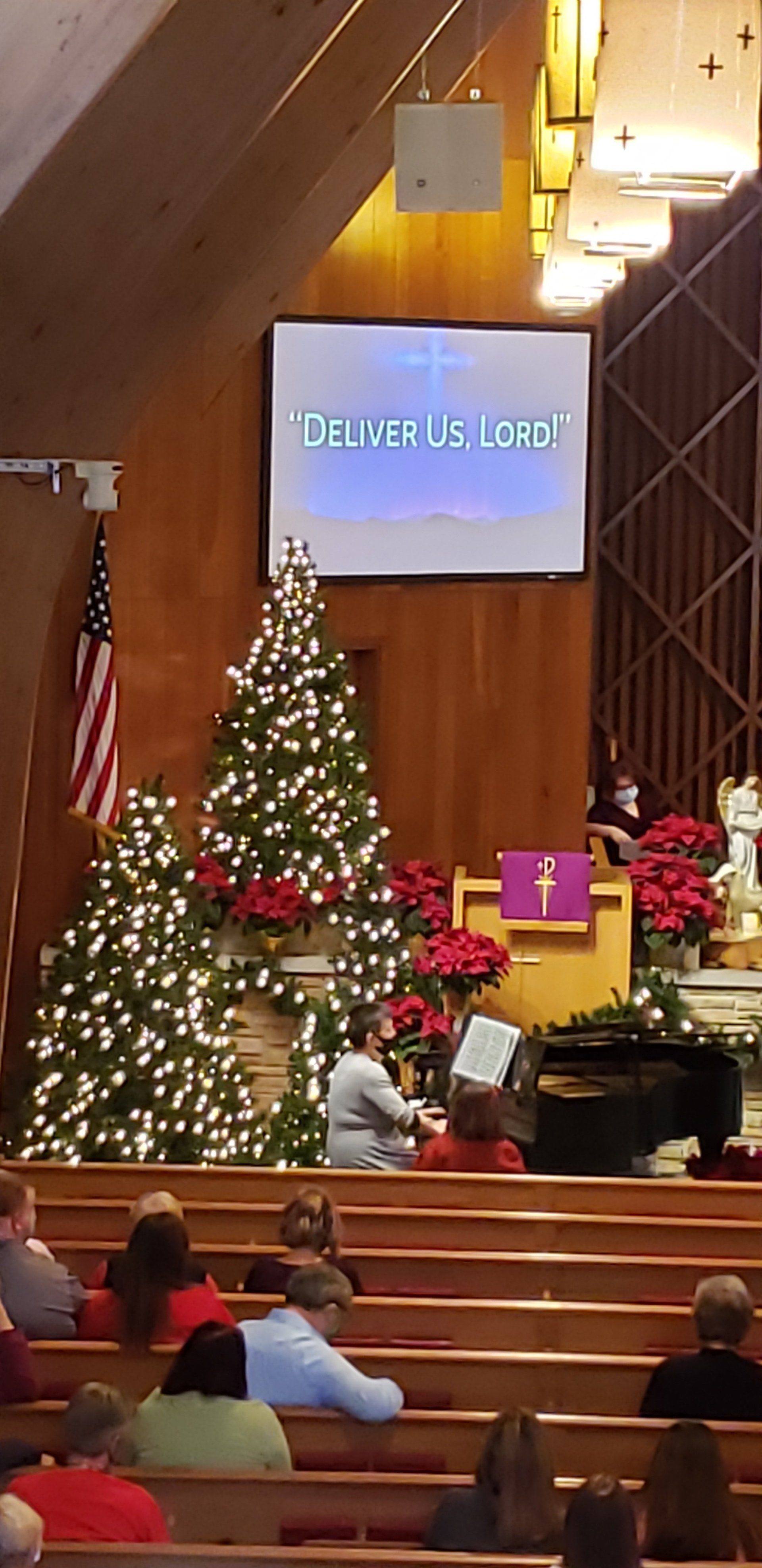 Church sanctuary with Christmas tree, wreaths, and a projection screen reading “Welcome”