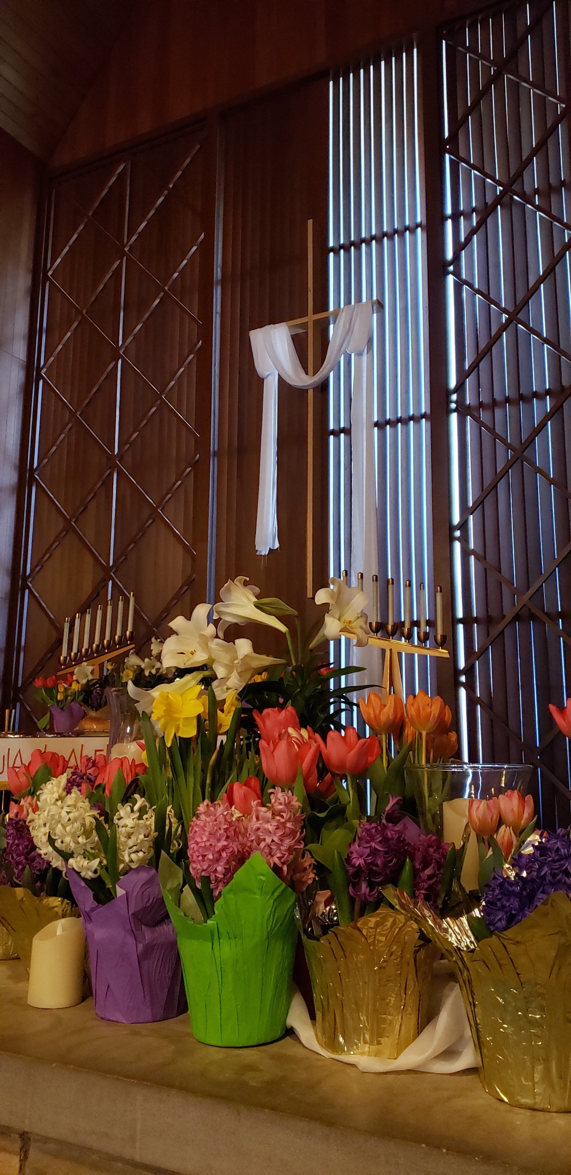 Colorful flower bouquets in buckets under a window with wooden lattice and sheer curtains