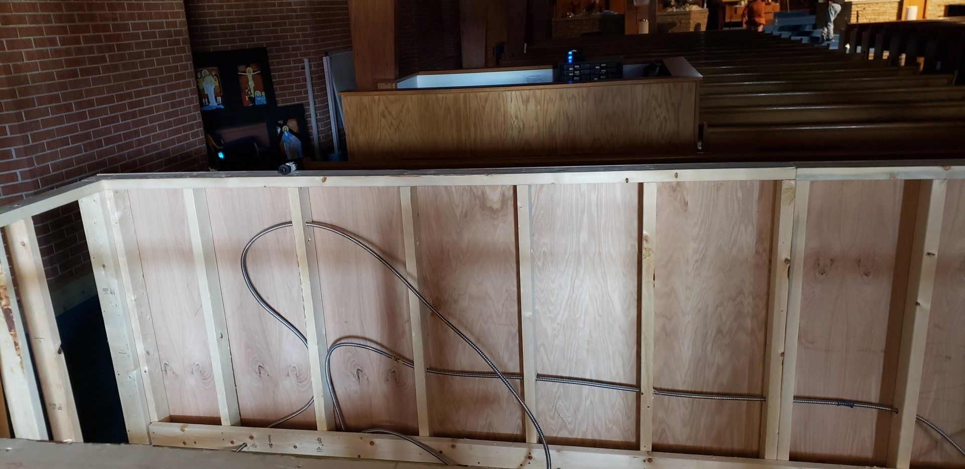 Bare wooden partition with exposed studs in an unfinished room, with a large coil of wire draped over it.