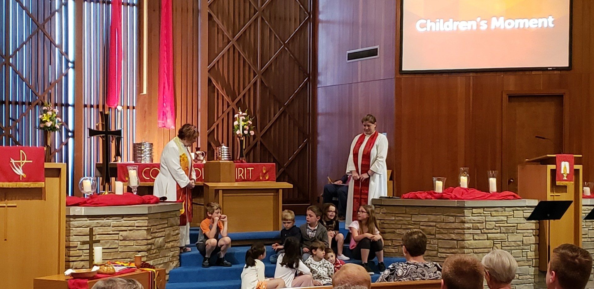 Children’s moment at church with clergy on stage and children seated in the congregation