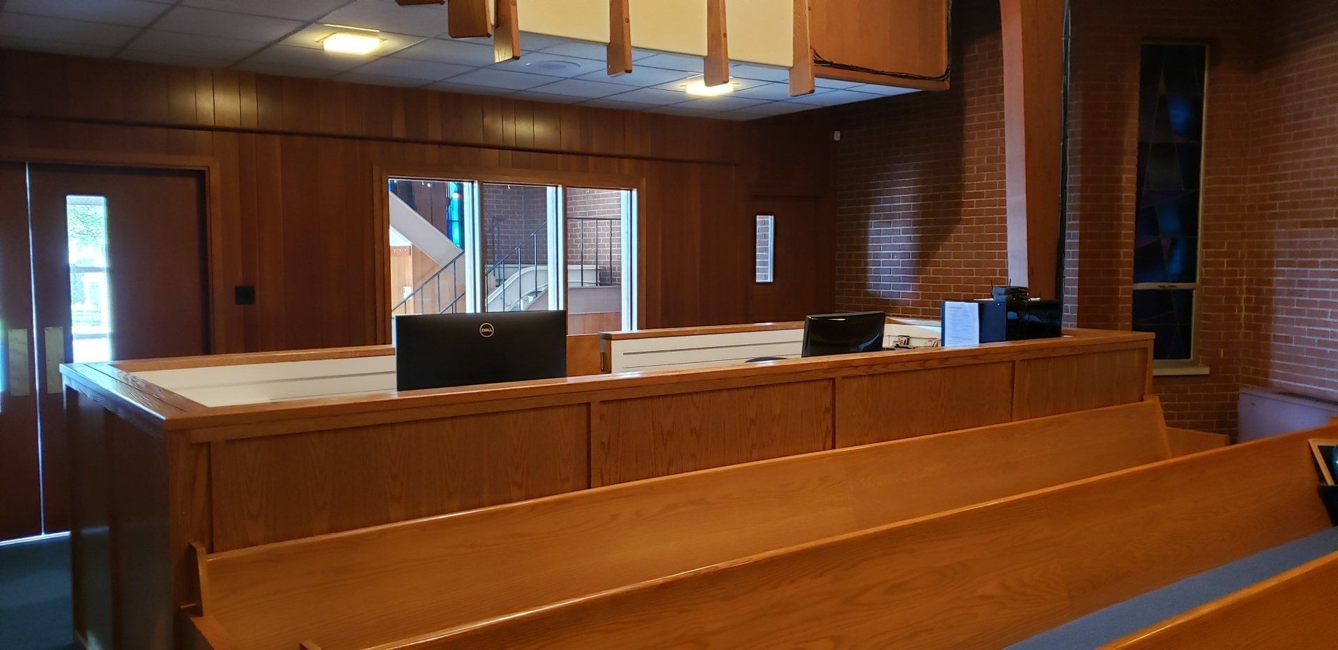 Empty wooden church sanctuary with pews, altar, and stained-glass windows