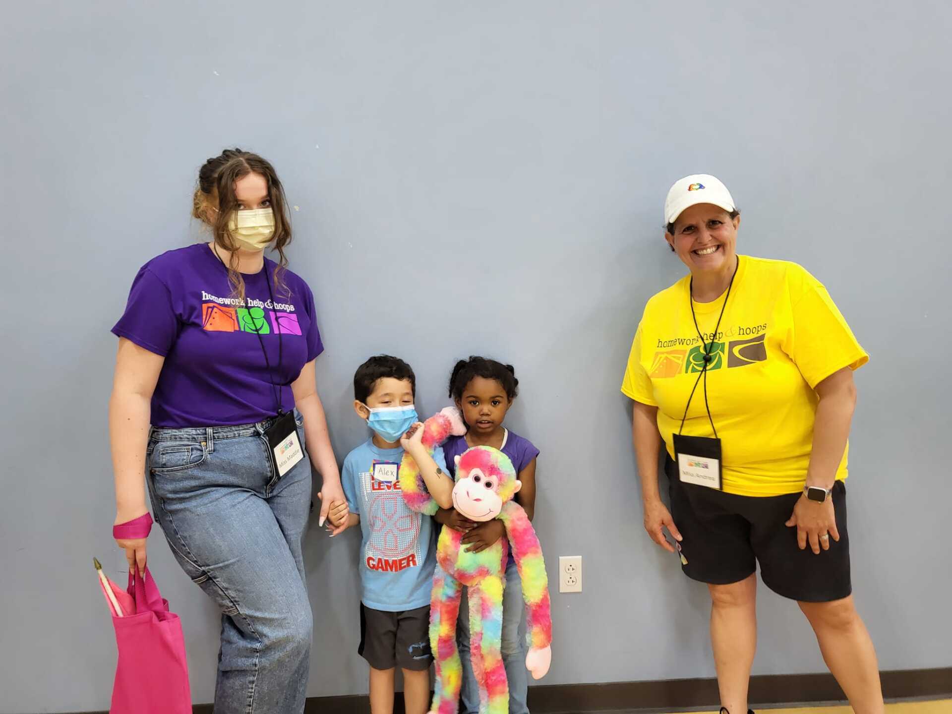 Three people and two children posing indoors, one child holding a colorful stuffed toy.
