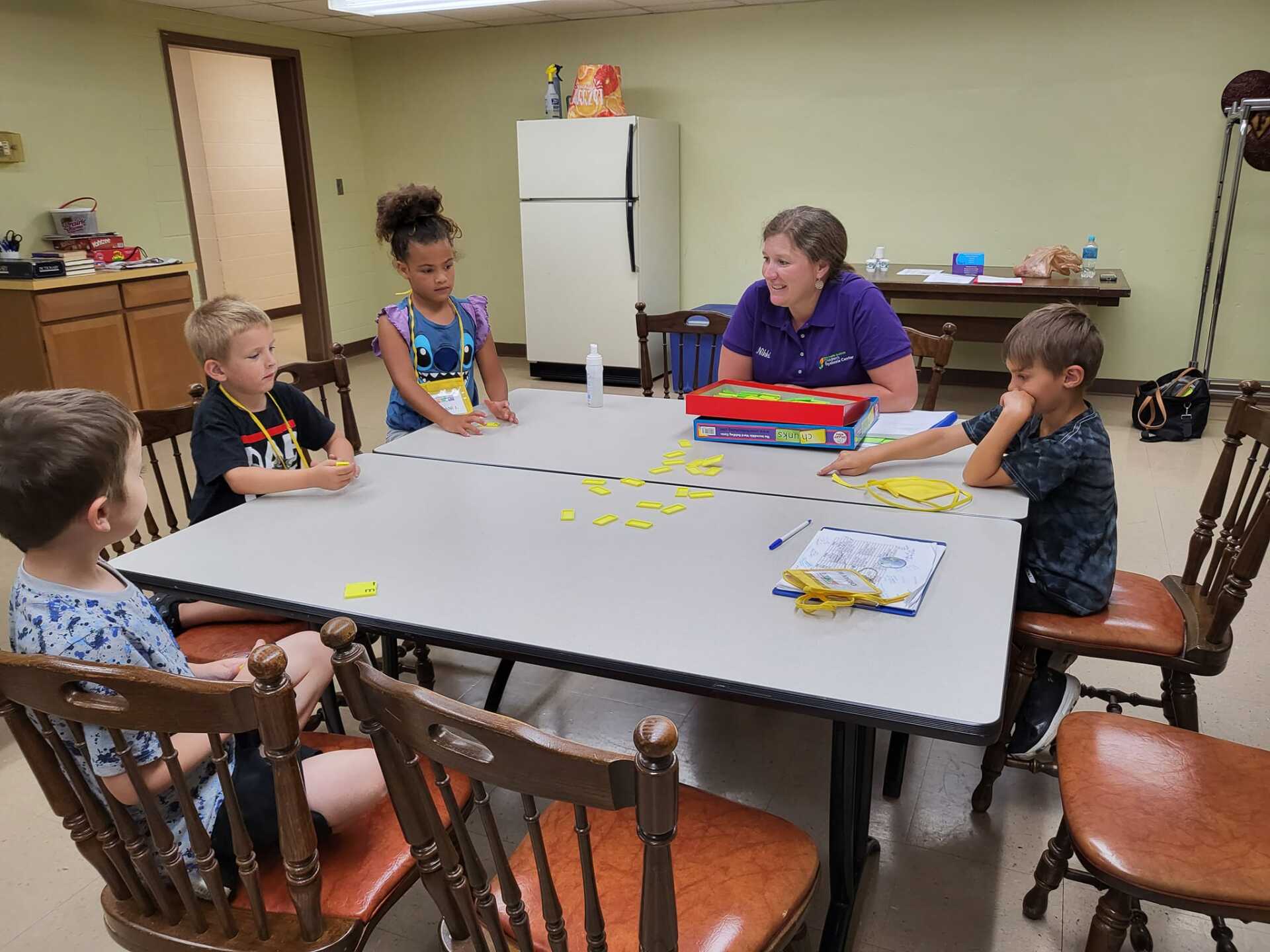 Children playing a board game around a table in a classroom or rec room