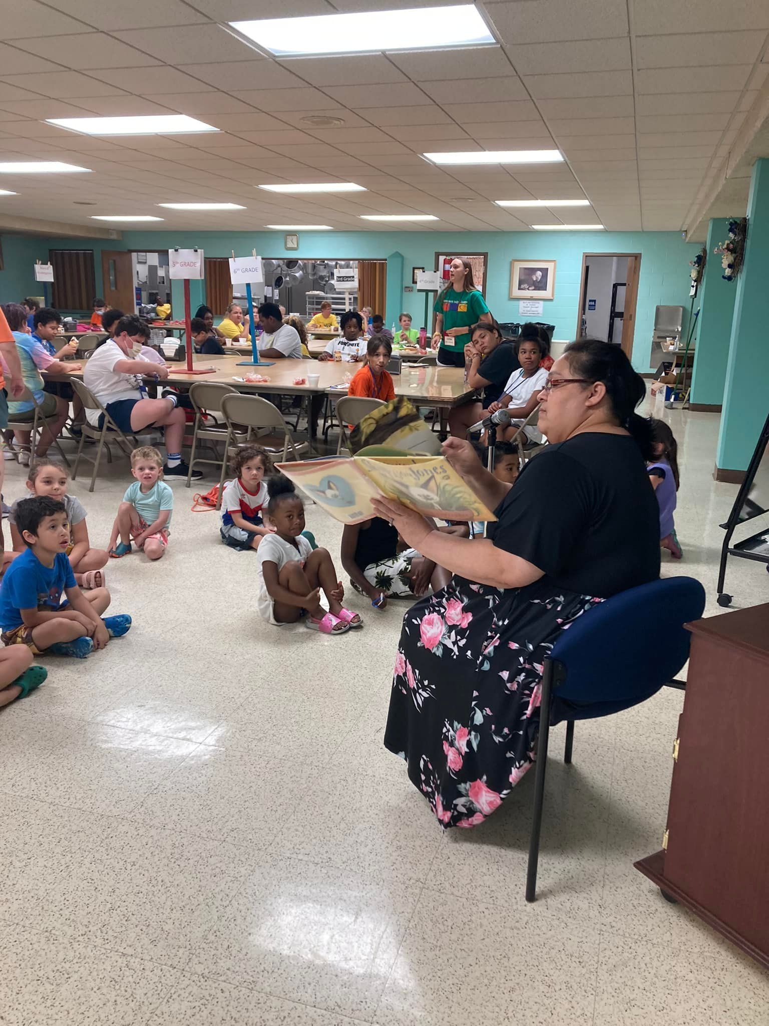 Woman reads to children seated on the floor in a bright community room.