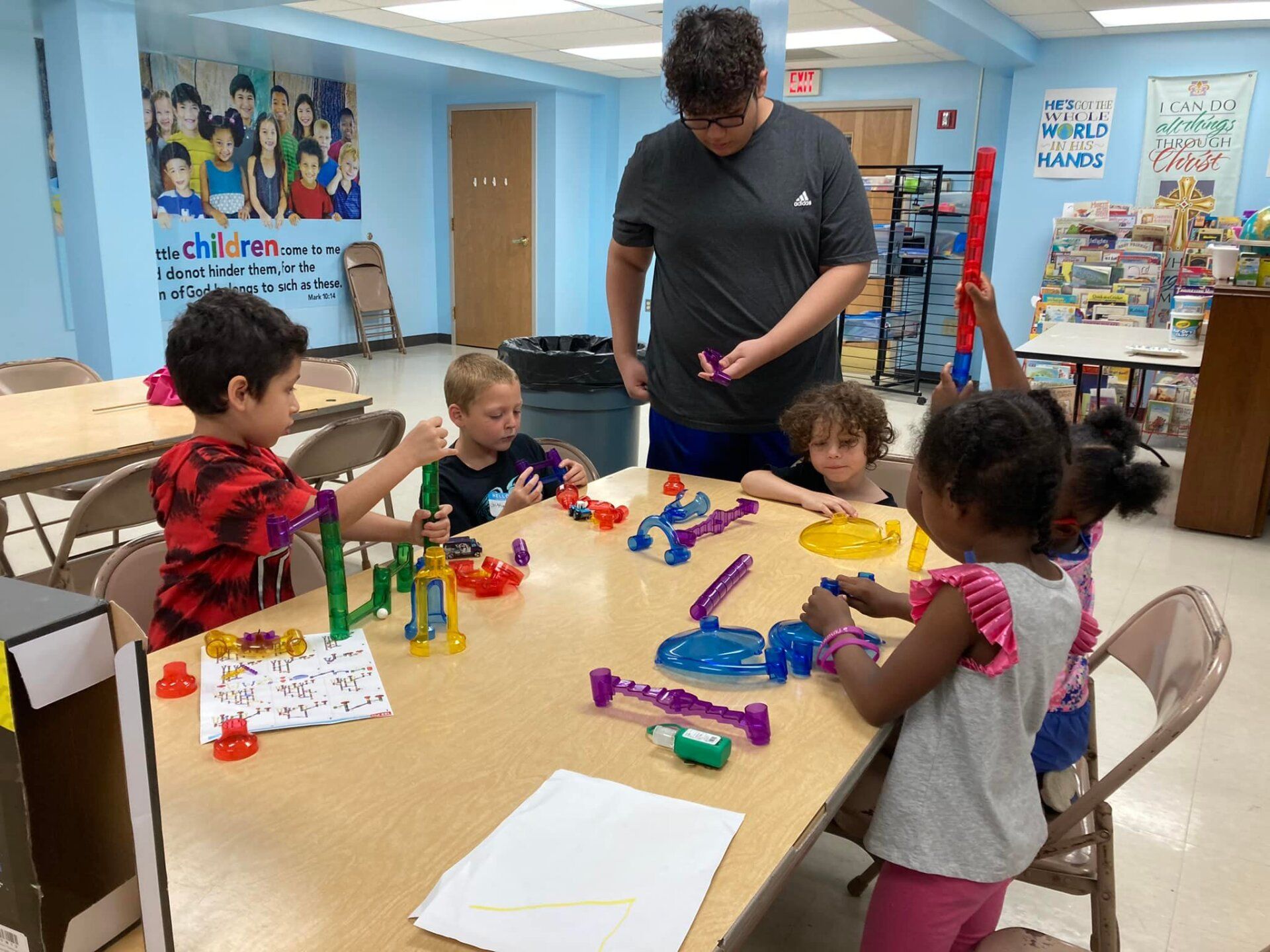 Adult helping children build colorful toys at a classroom table