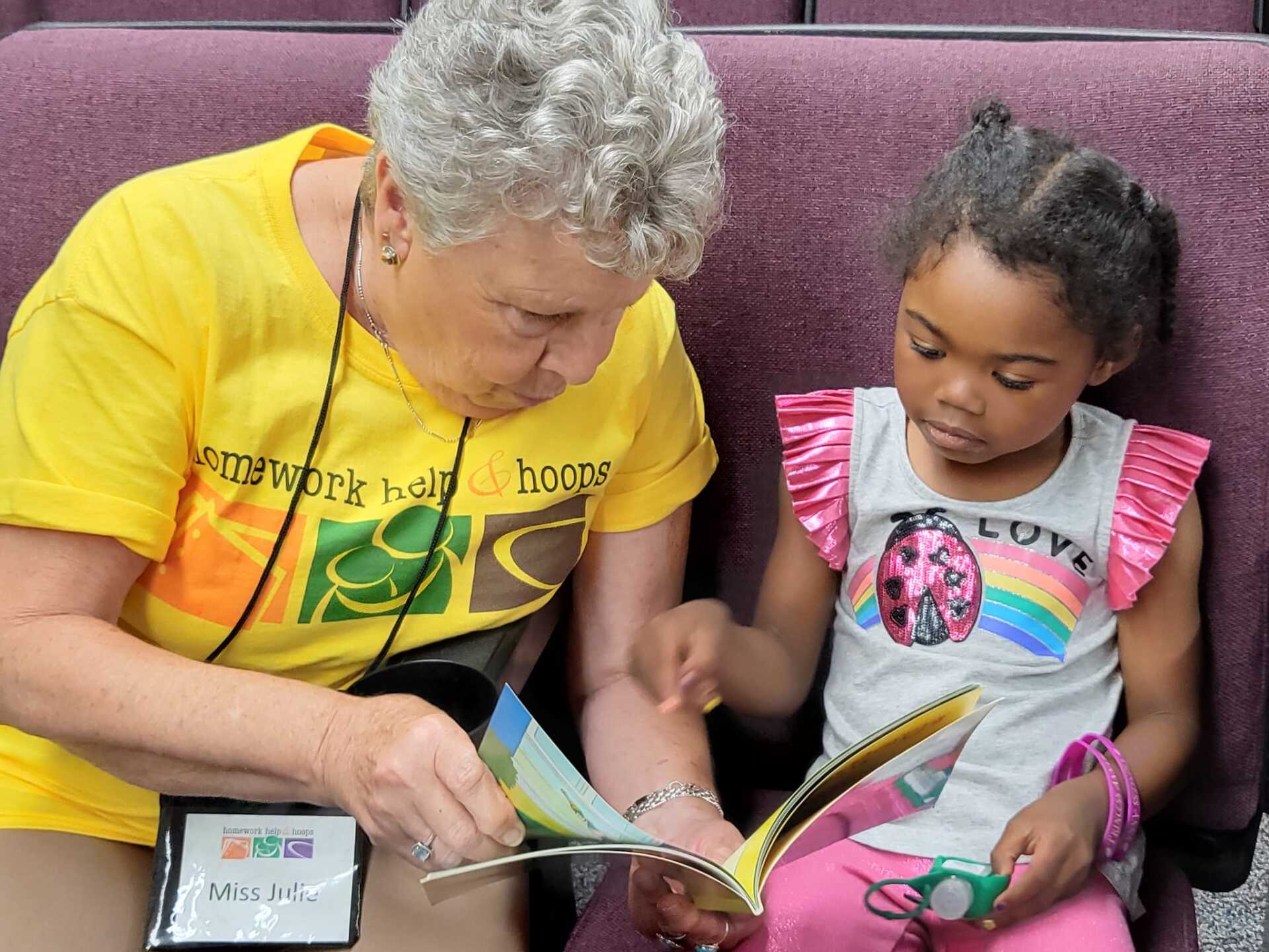 Two people reading a colorful book together on a couch