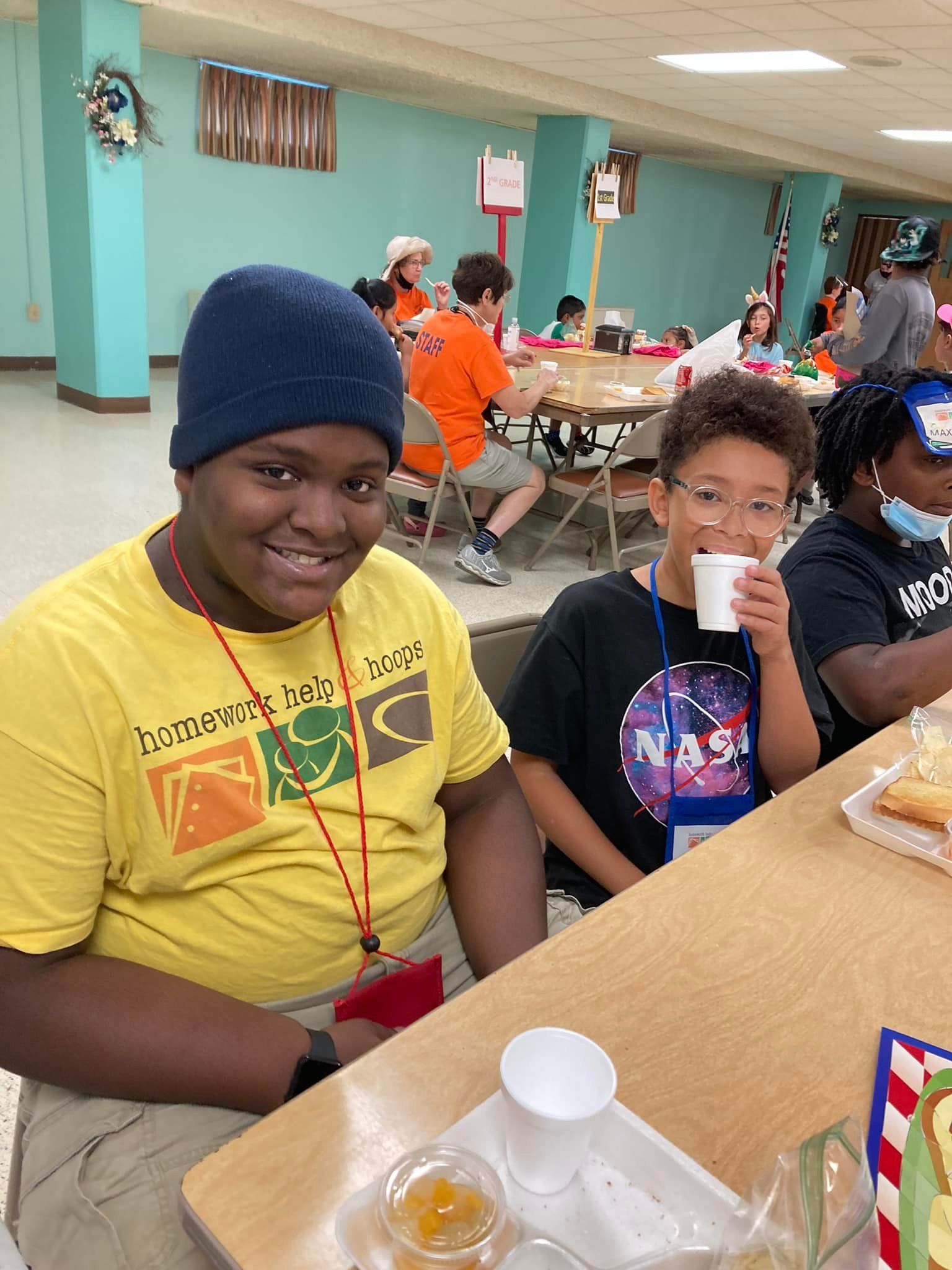 Two people seated at a table in a bright cafeteria, smiling and eating snacks.