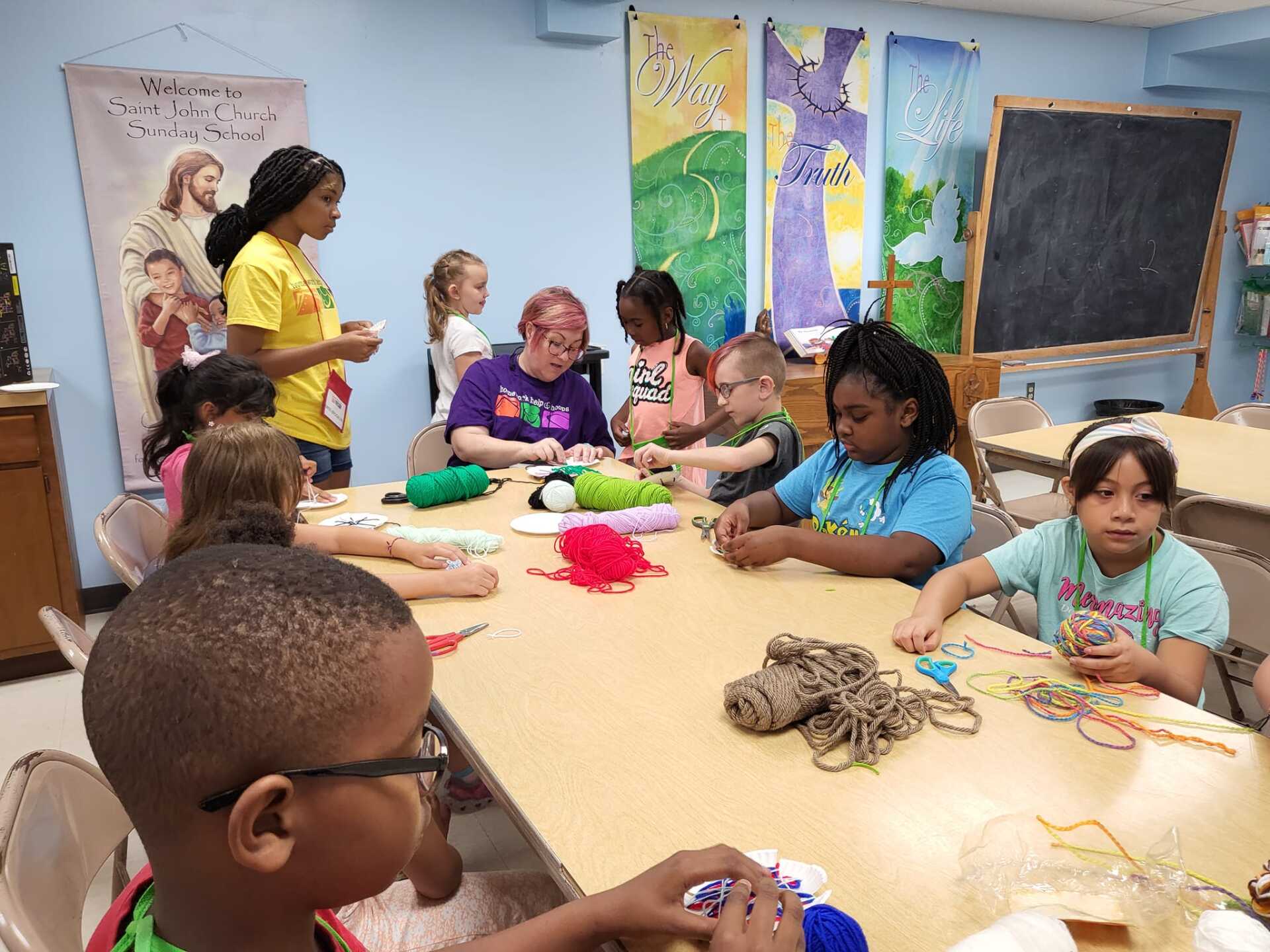 People seated around a table doing arts and crafts in a colorful classroom.
