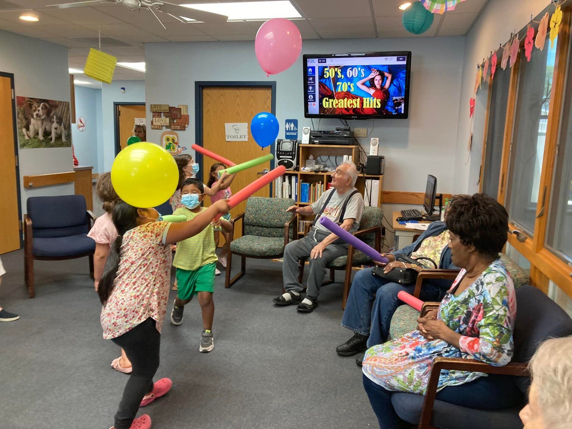People in a community room play with colorful balloons while seated and standing