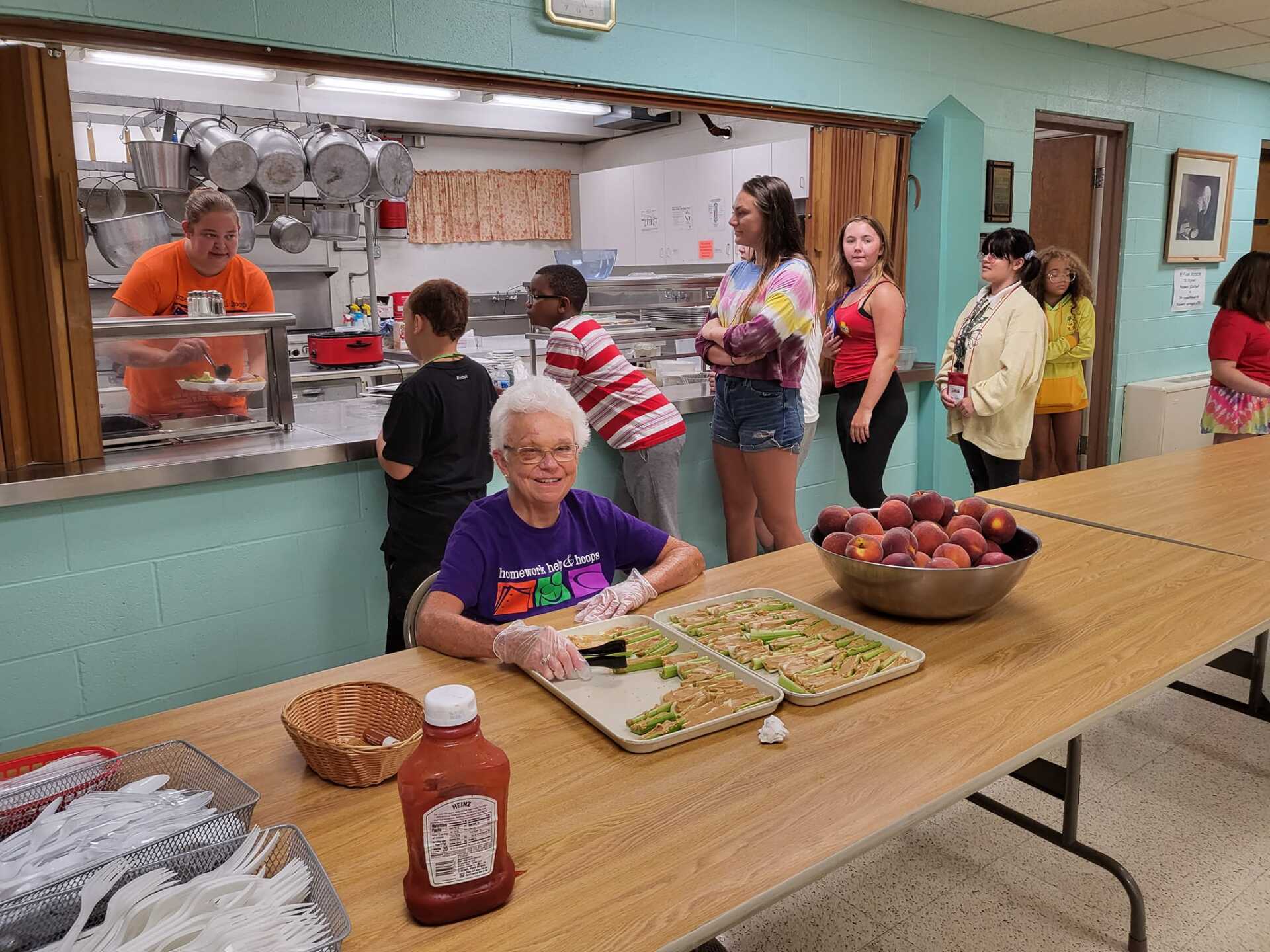Senior center lunch line with volunteers serving food at a buffet table