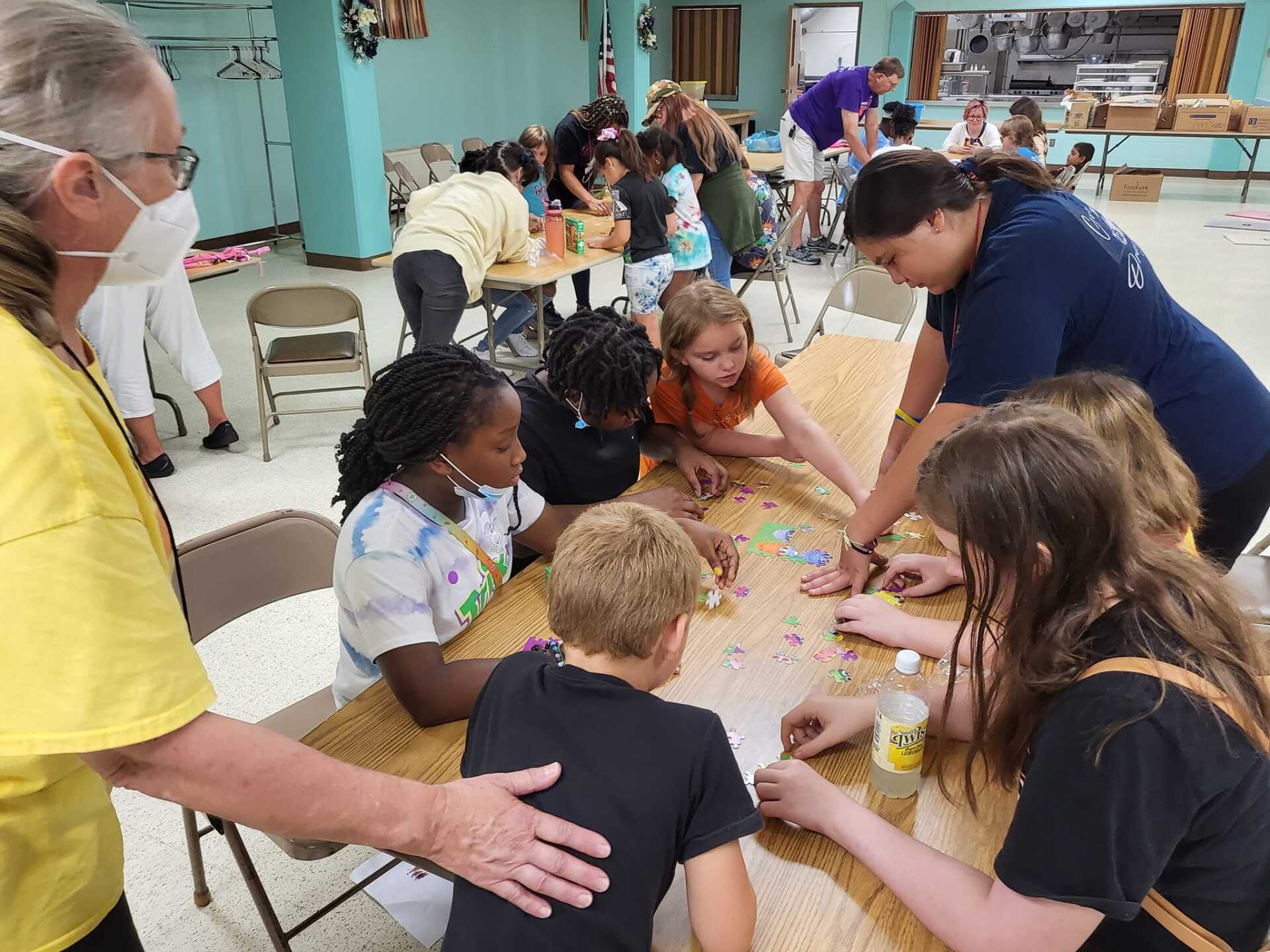 People gathered around a table doing a colorful craft activity indoors.