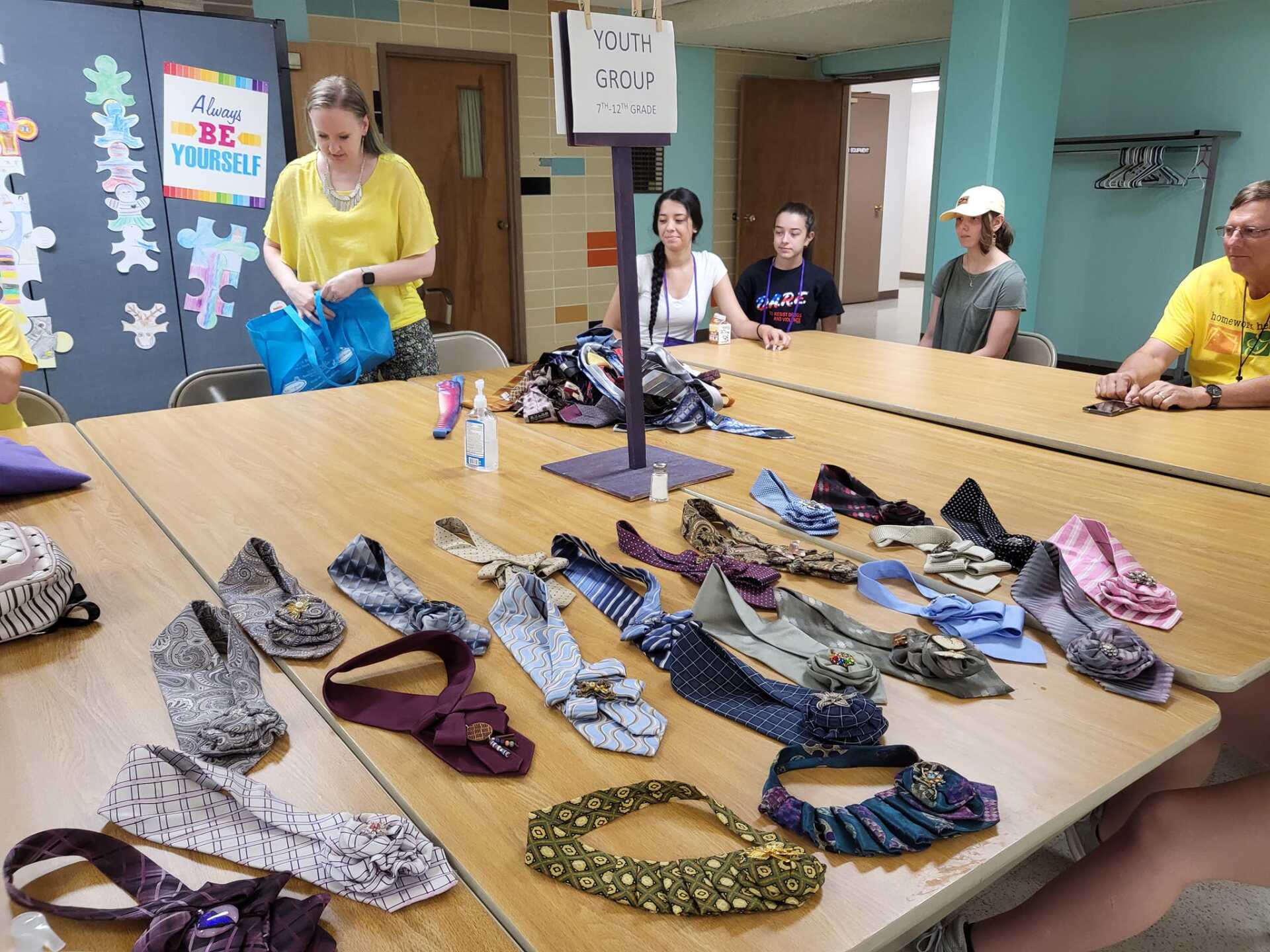 Tables covered with numerous shoes while people stand in a room, likely for sorting or a school activity.