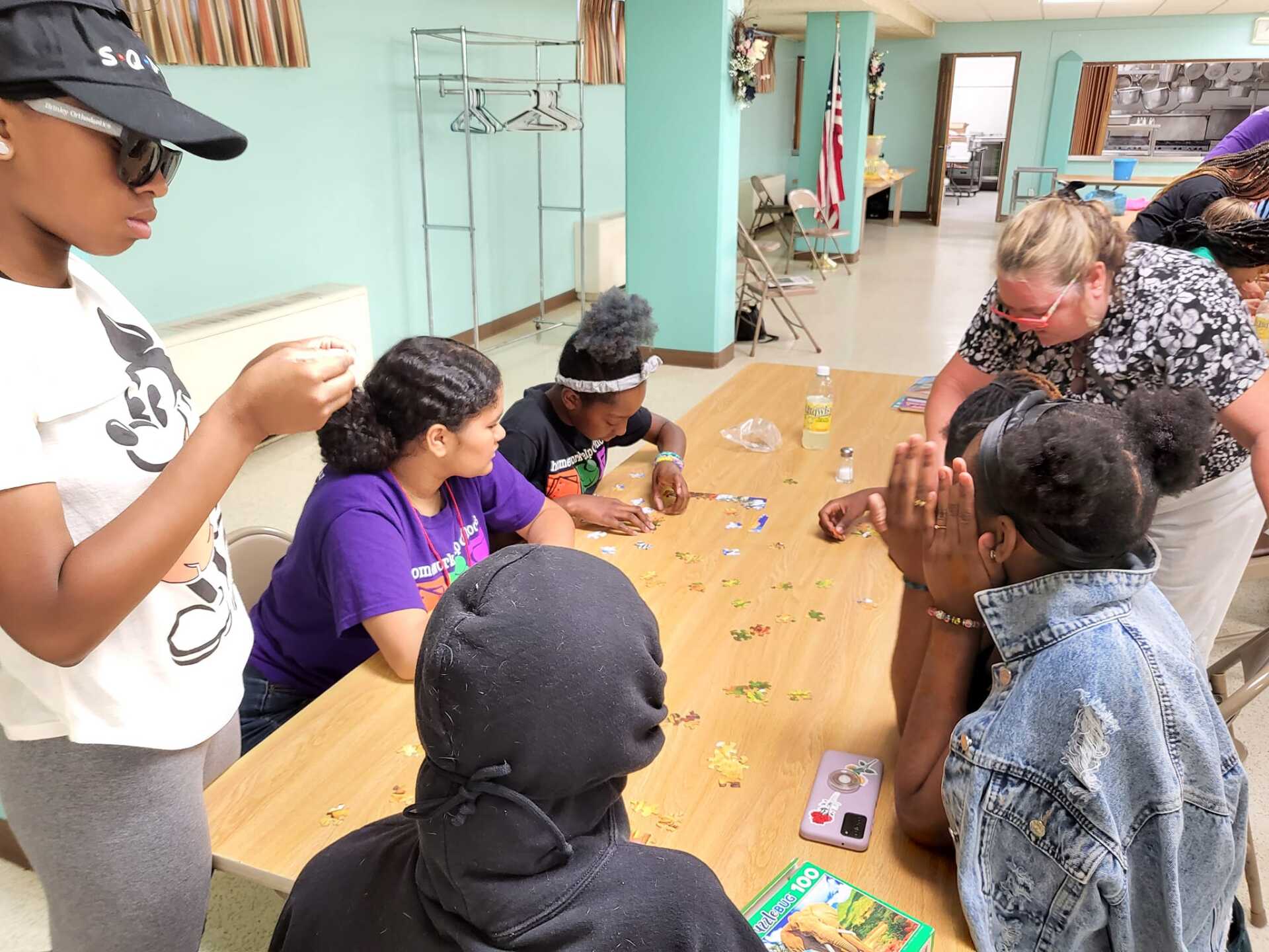 Group gathered around a table doing an art/craft activity in a bright room.