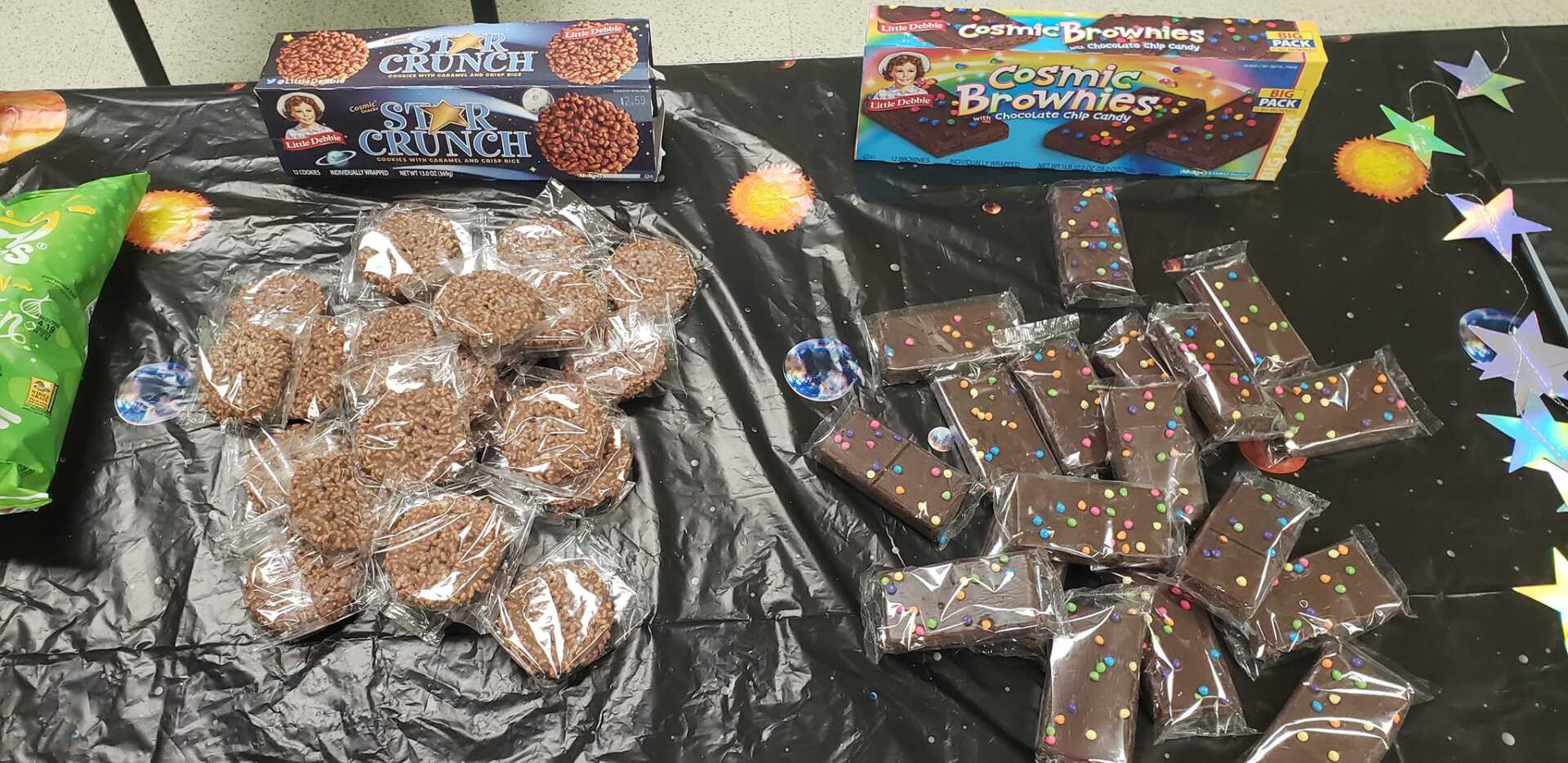 Two bags of candy on a starry black tablecloth, one brown and one dark chocolate-covered treats