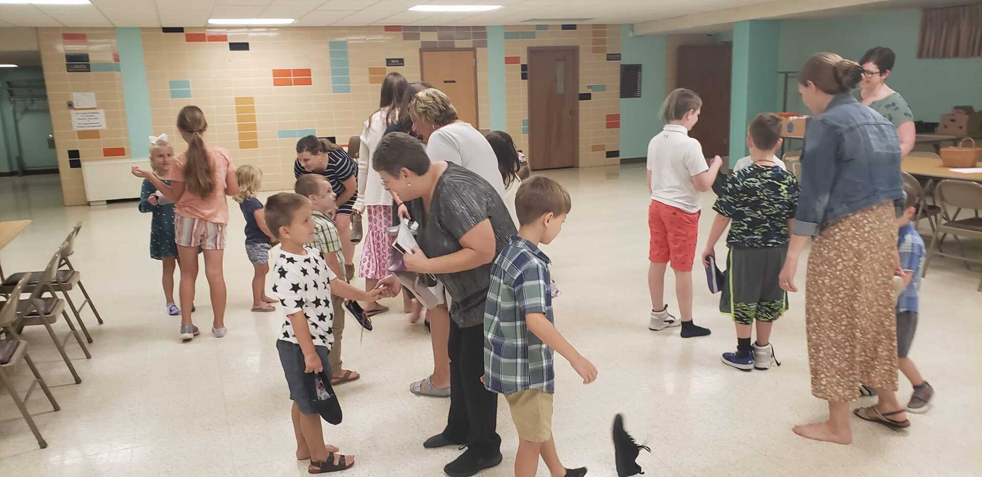 People dancing in a community room, with a few adults and children gathered near the walls.