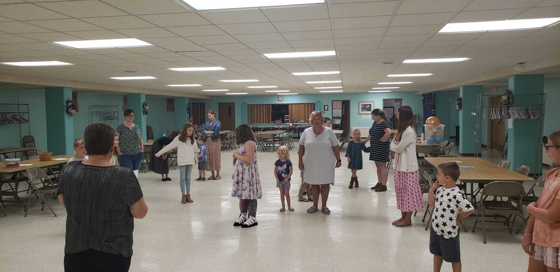 People practicing dance in a bright community hall with mirrors and teal walls